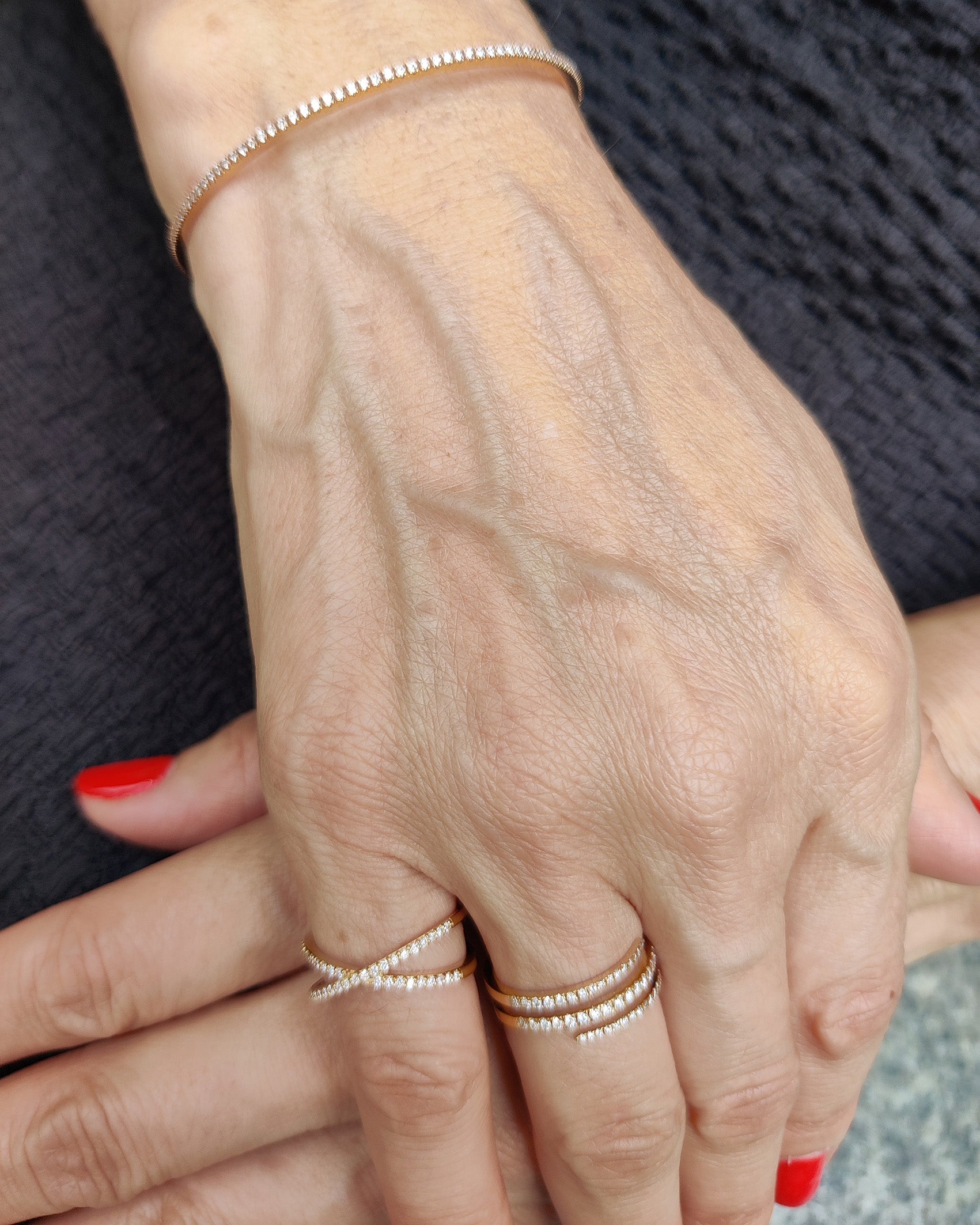 Elegant push-on tennis bangle with diamonds stacked with rings on a hand.
