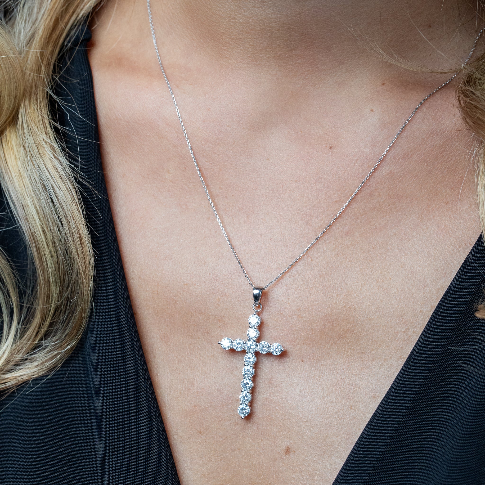 White gold necklace with brilliant cut diamonds on a person wearing a black top.
