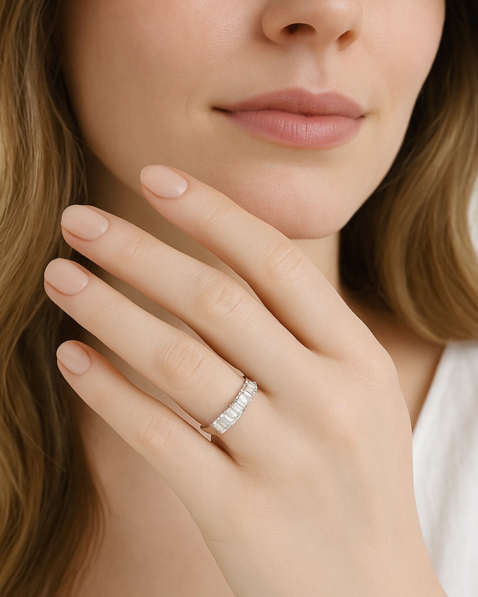 Close-up of a woman's hand wearing a seven stone emerald cut diamond eternity ring, showcasing elegance and sparkle.