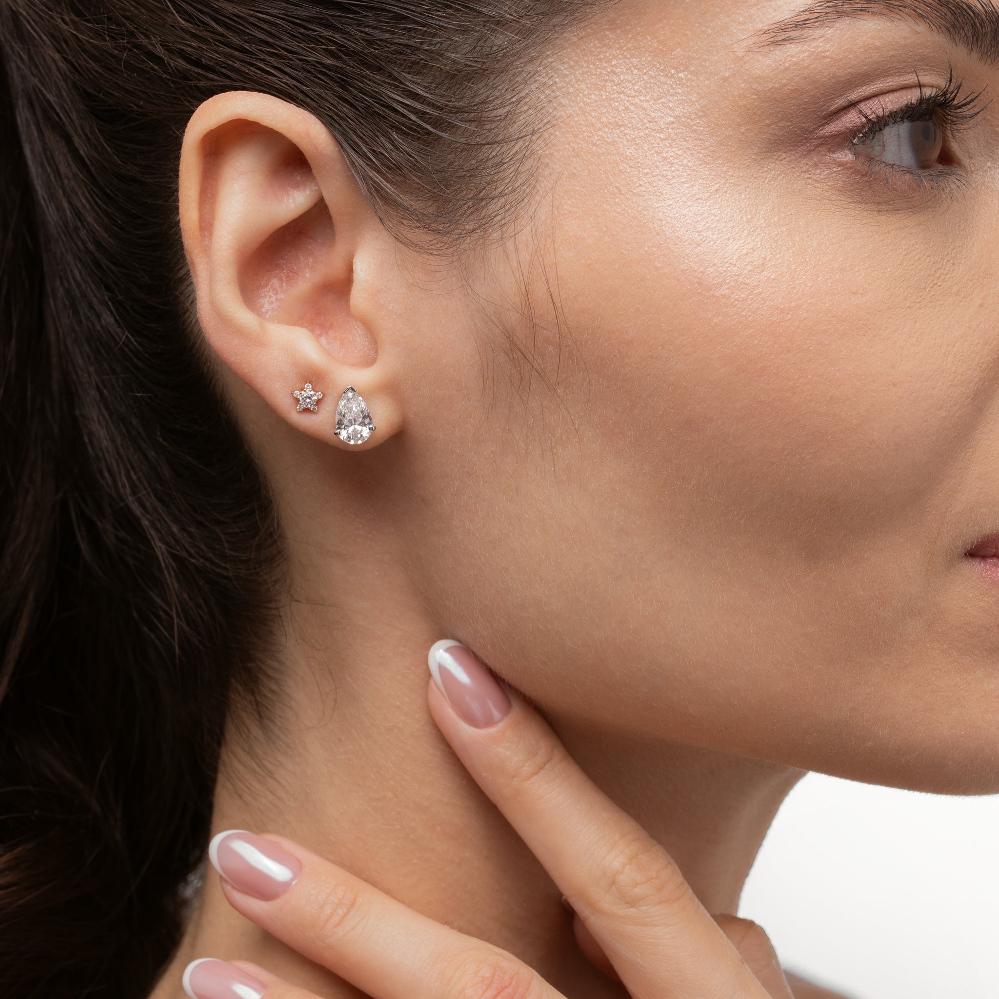 Model showcasing Pear Diamond Stud Earrings and a star-shaped earring, highlighting luxurious diamond earrings.