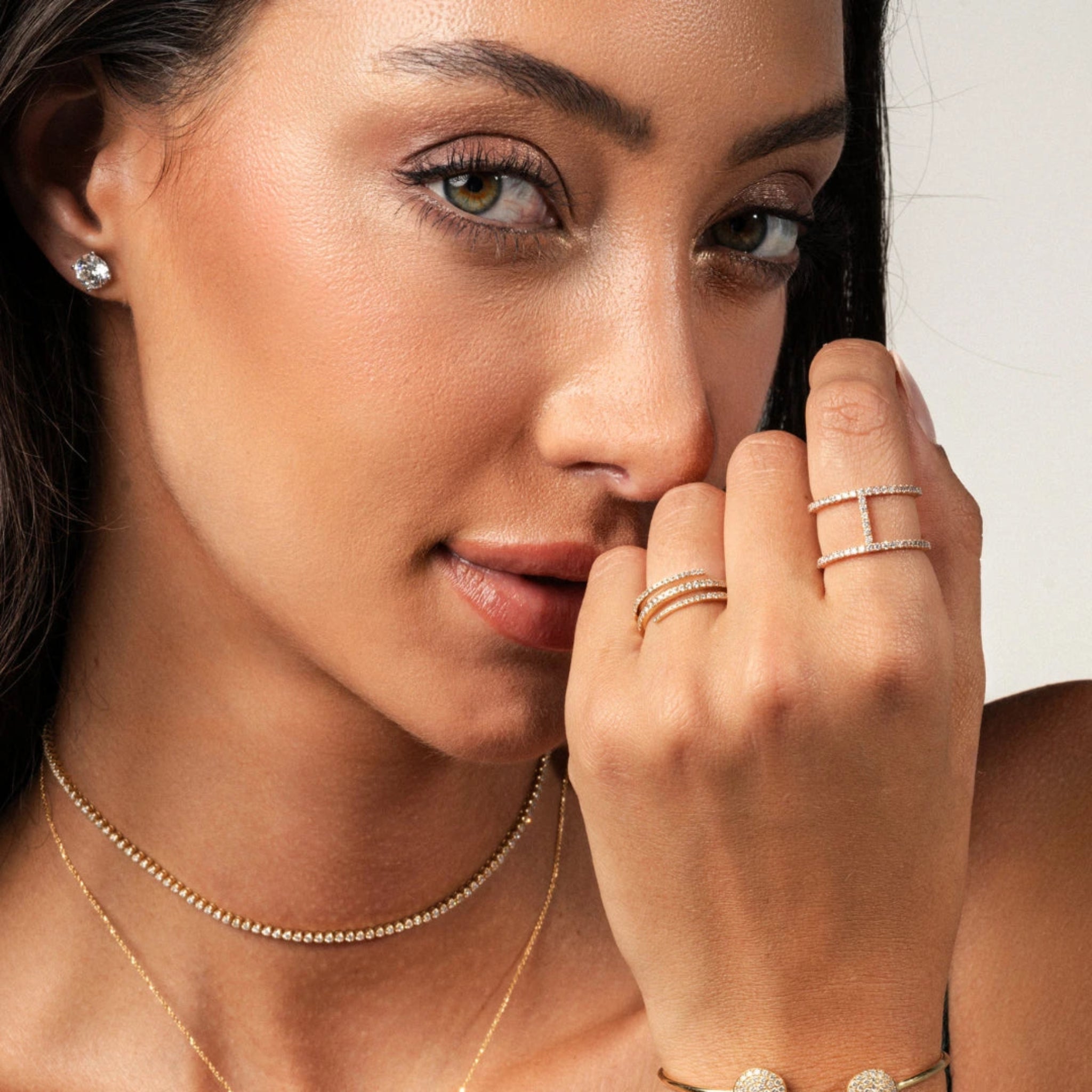 Model showcasing elegant diamond ring alongside gold jewelry, highlighting delicate sparkle and stylish accessories.