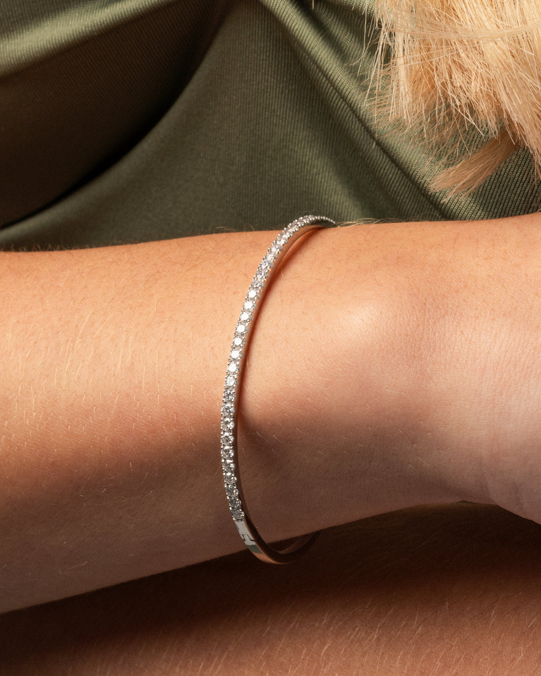Diamond tennis bangle featuring diamonds set in solid 18ct gold worn on a wrist.