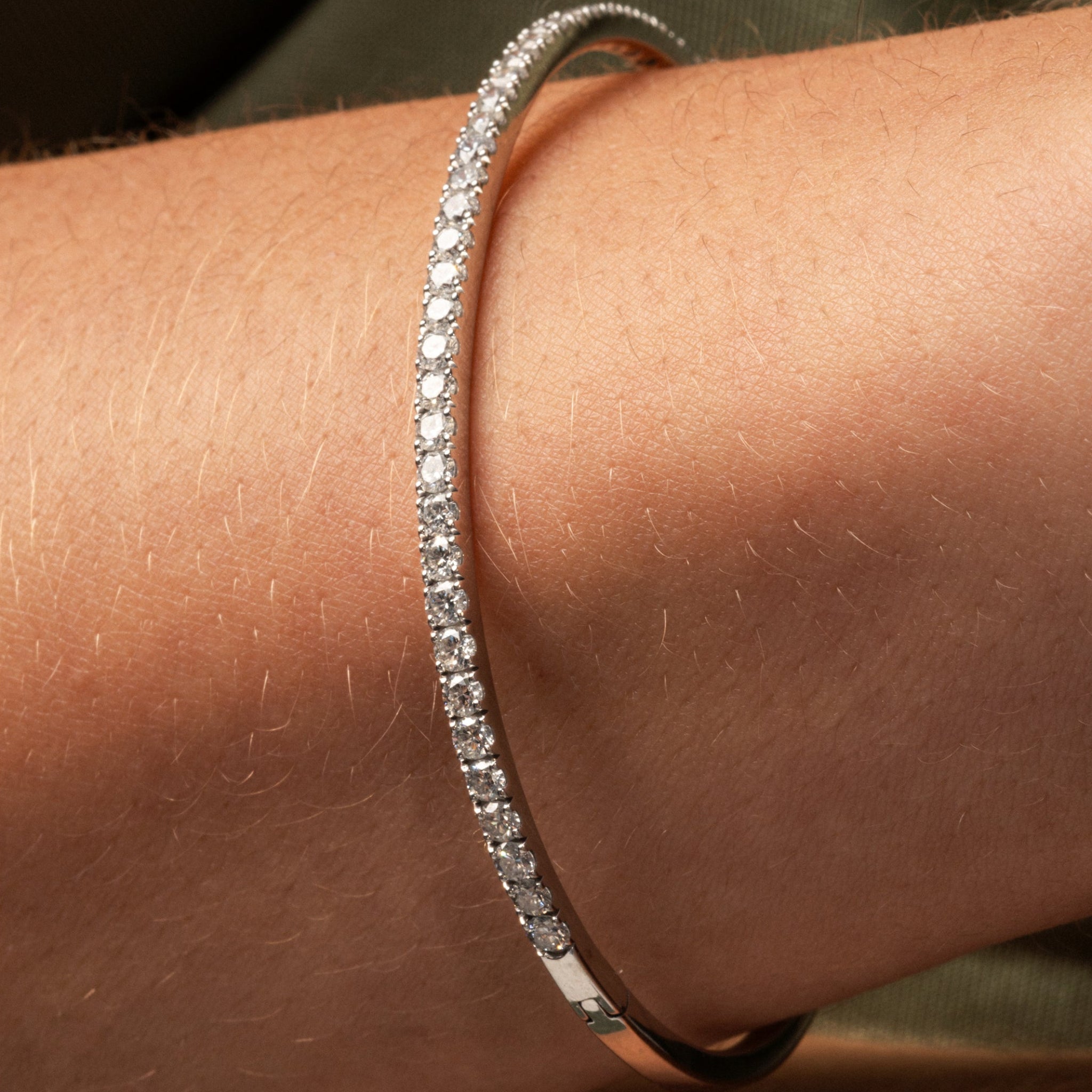 Diamond tennis bangle featuring diamonds set in solid 18ct gold worn on a wrist.
