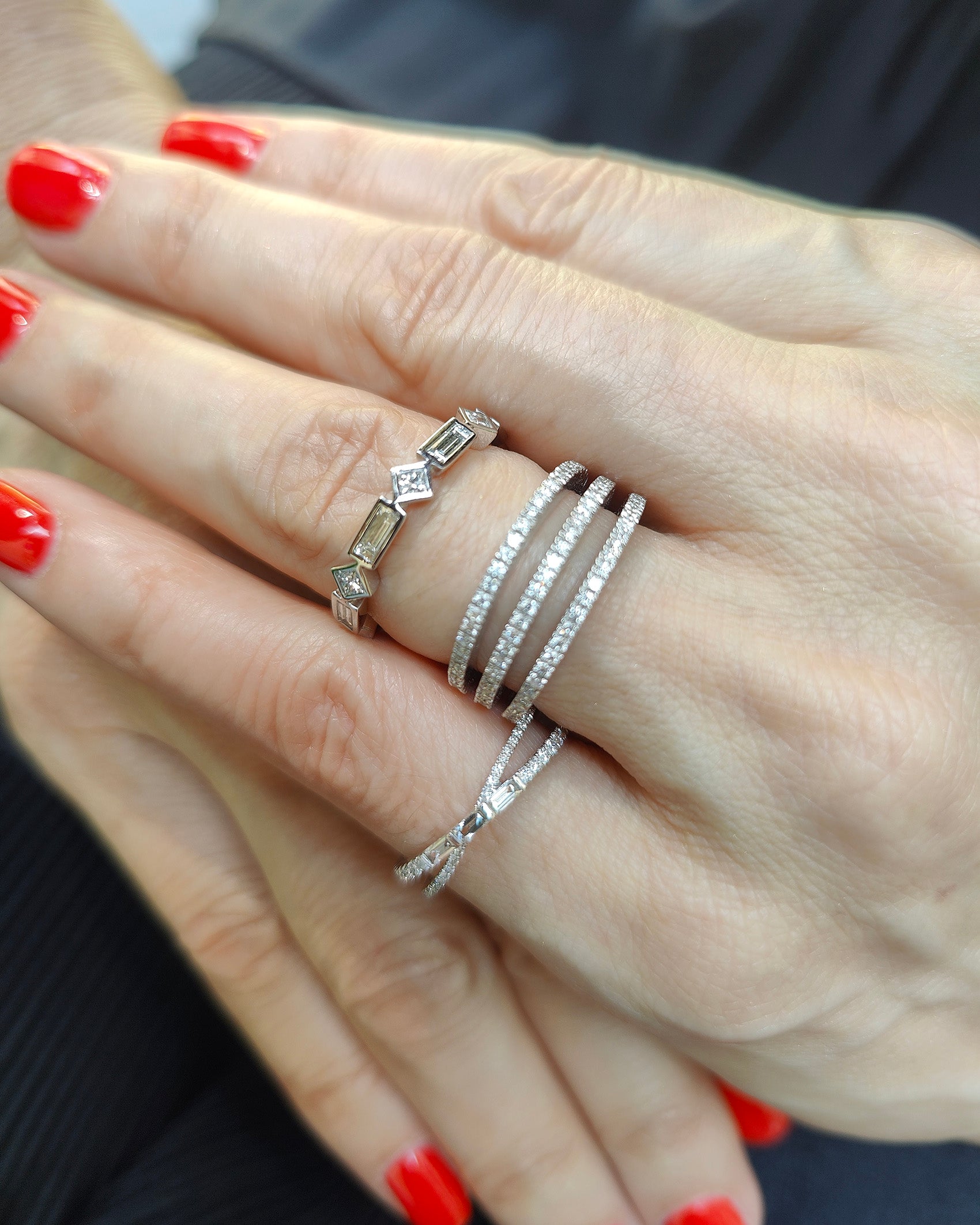 Elegant hands adorned with multiple stylish diamond rings showcasing sparkle and sophistication.