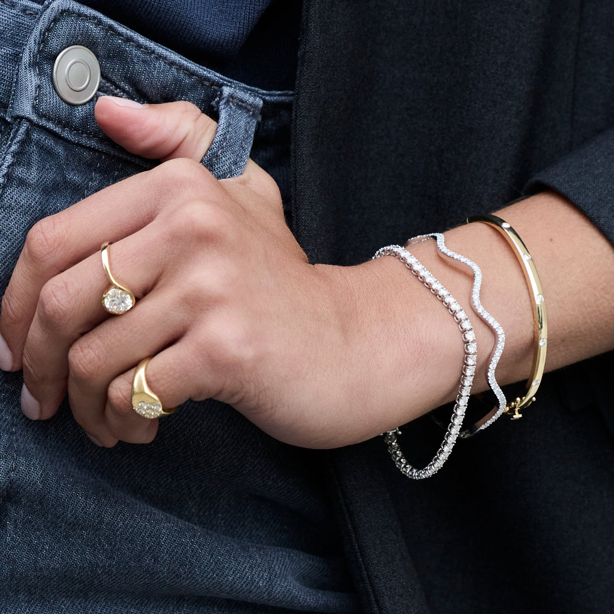 Stylish hand showcasing the Diamond Wave Bangle alongside gold rings, creating a chic look with diamond sparkle.