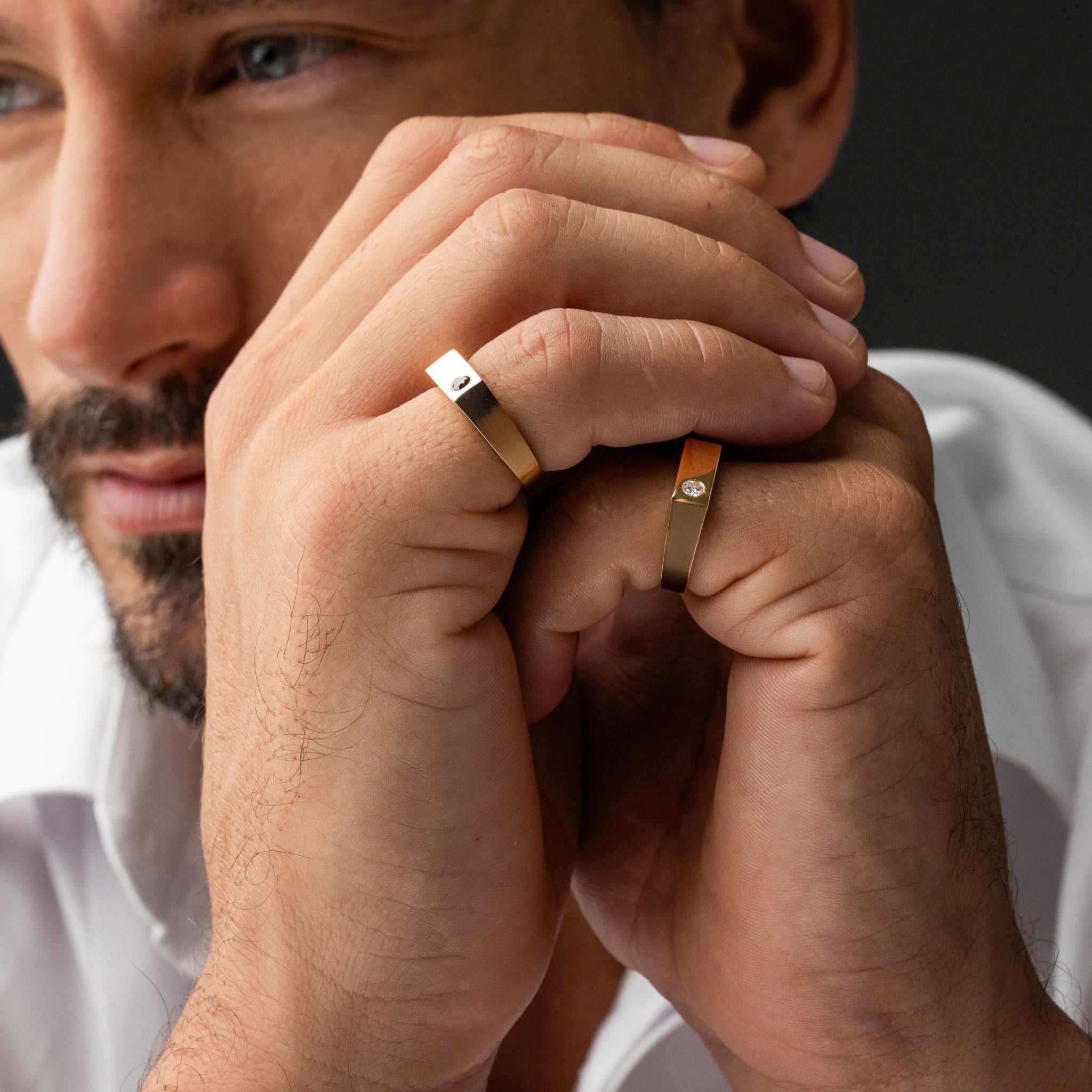 Close-up of a man's hands with gold rings on a dark background