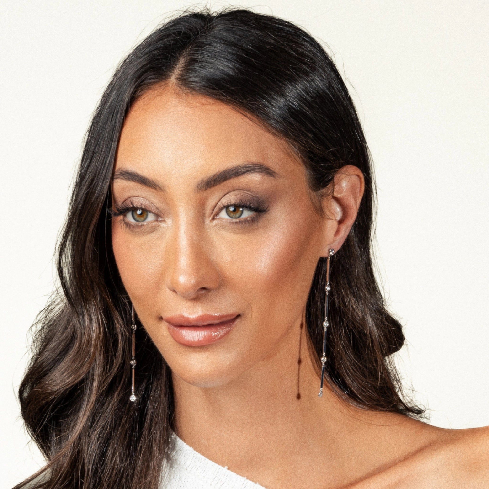 Elegant woman showcasing Cascade Diamond earrings in 18ct white gold, featuring a stunning cascading design.