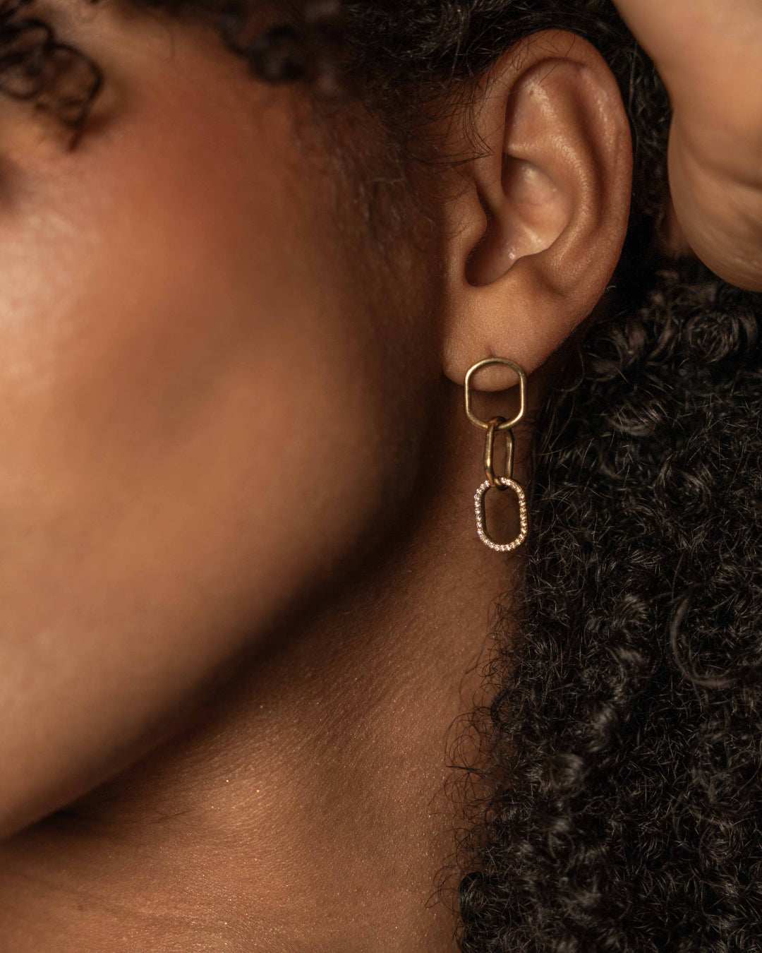 Close-up of model wearing chain link diamond earrings showcasing interlocking links in 18ct gold with certified diamond accent.