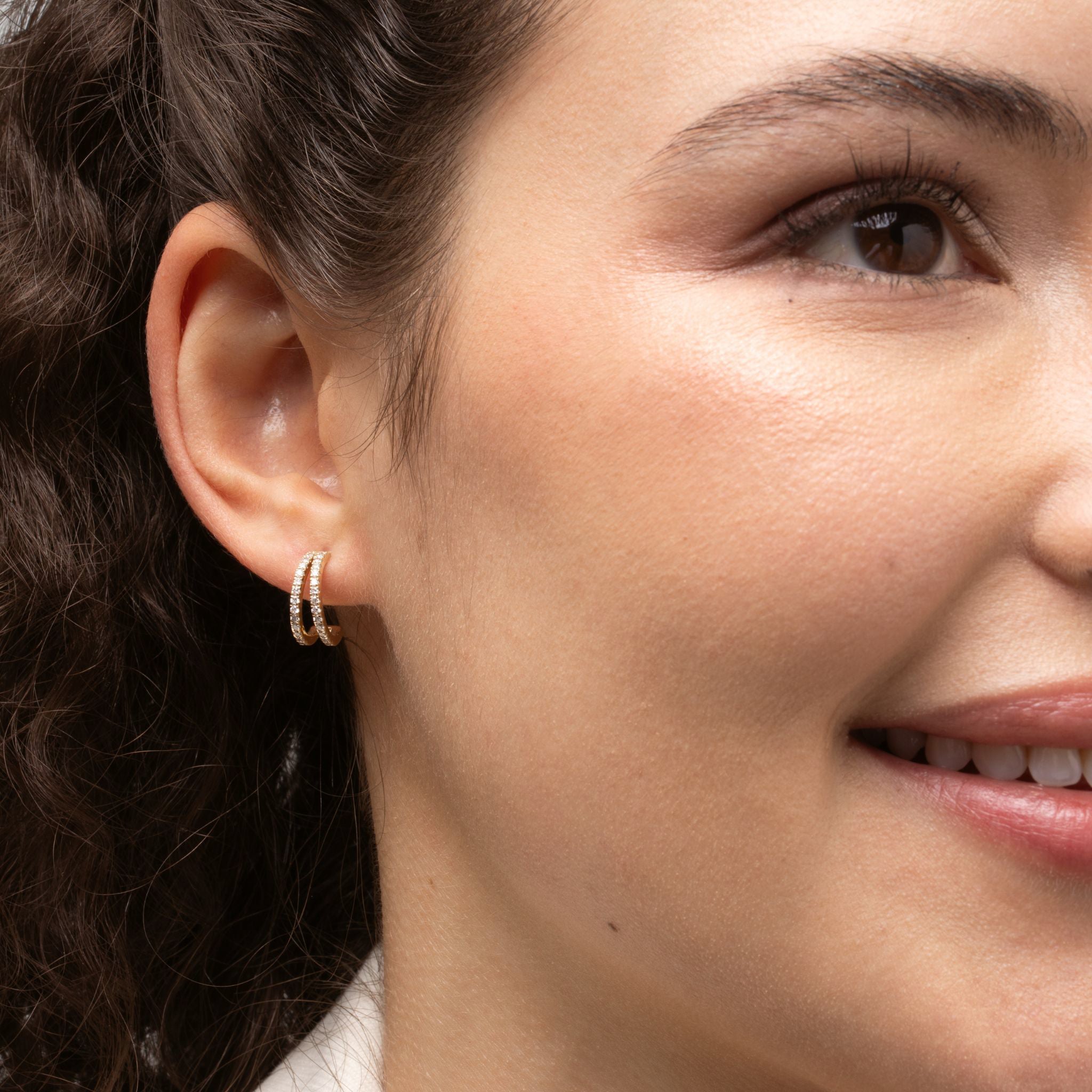 Close up of model wearing double row diamond huggies showcasing certified diamond earrings in 18ct gold.