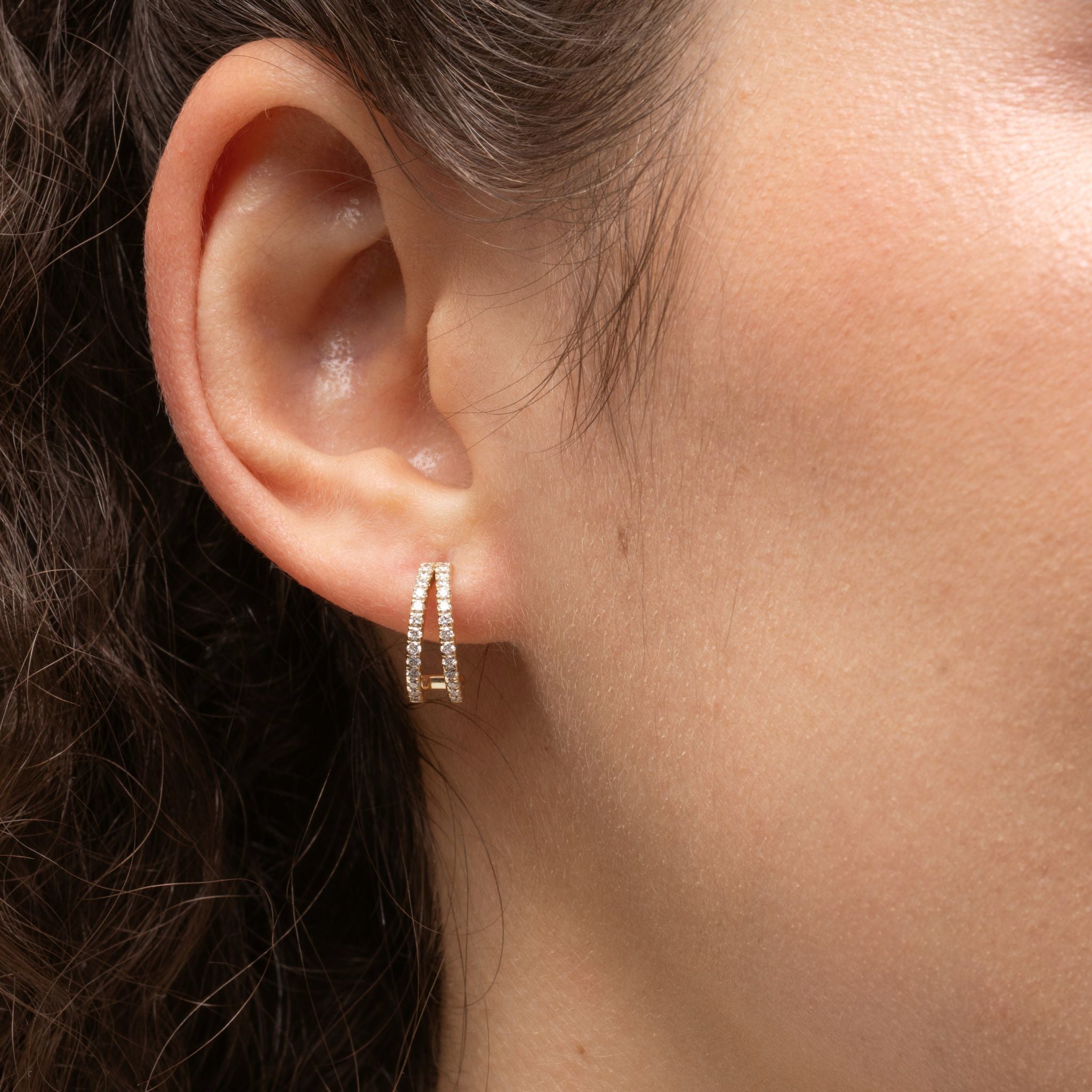 Close-up of a woman wearing elegant double row diamond huggies crafted with certified diamond earrings set in 18ct gold.