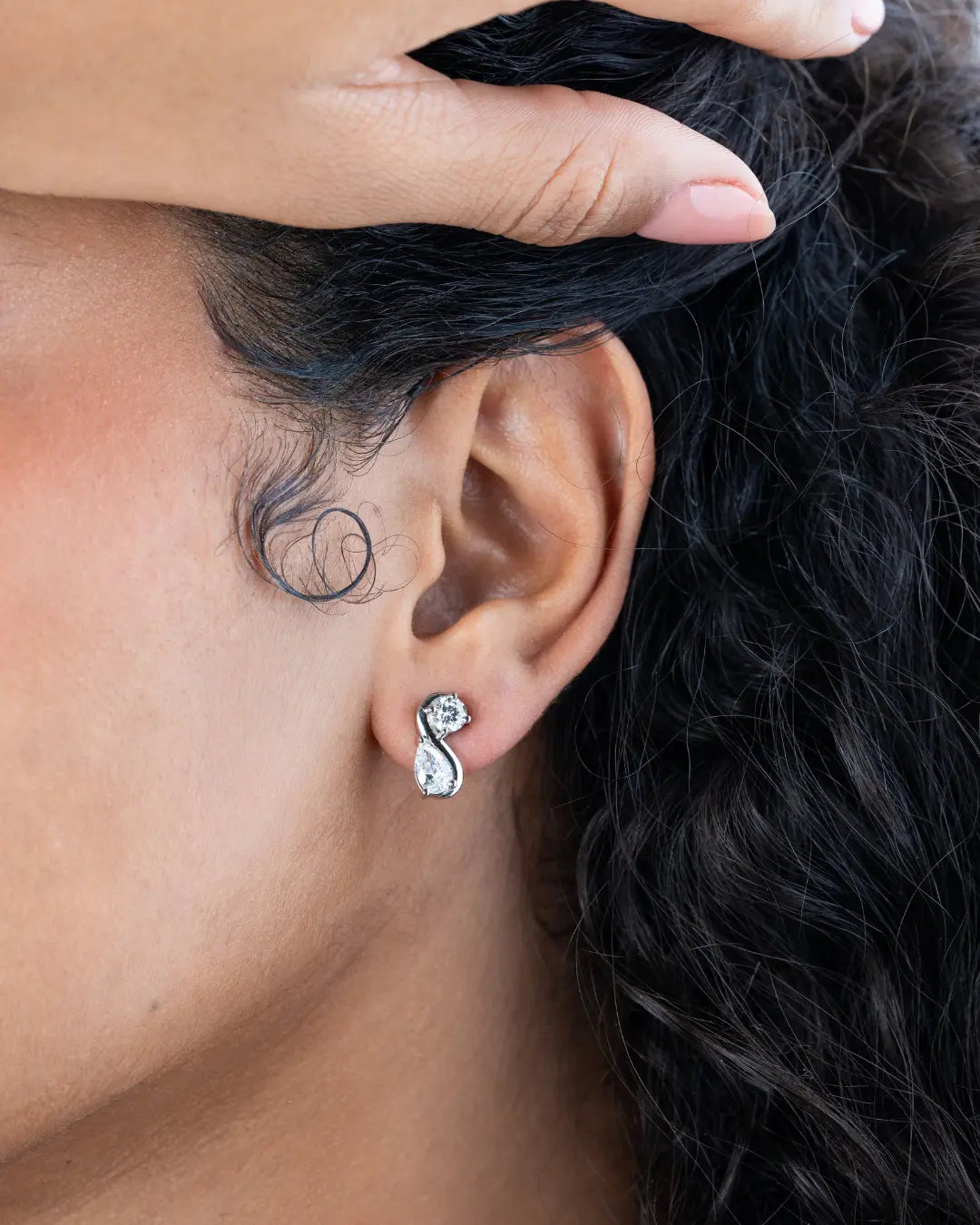 Close-up of an ear wearing a diamond earring with a blurred background