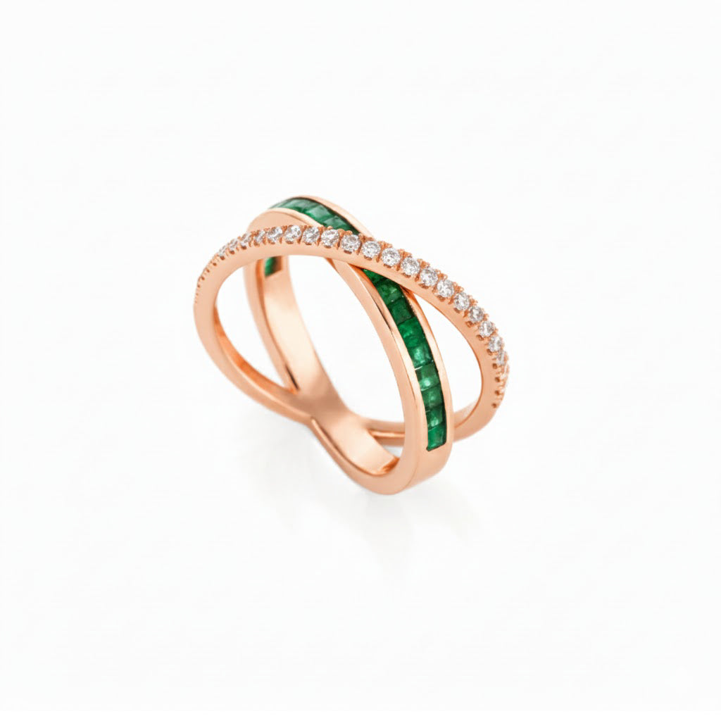 Rose gold criss cross ring with emeralds and small diamonds on a white background