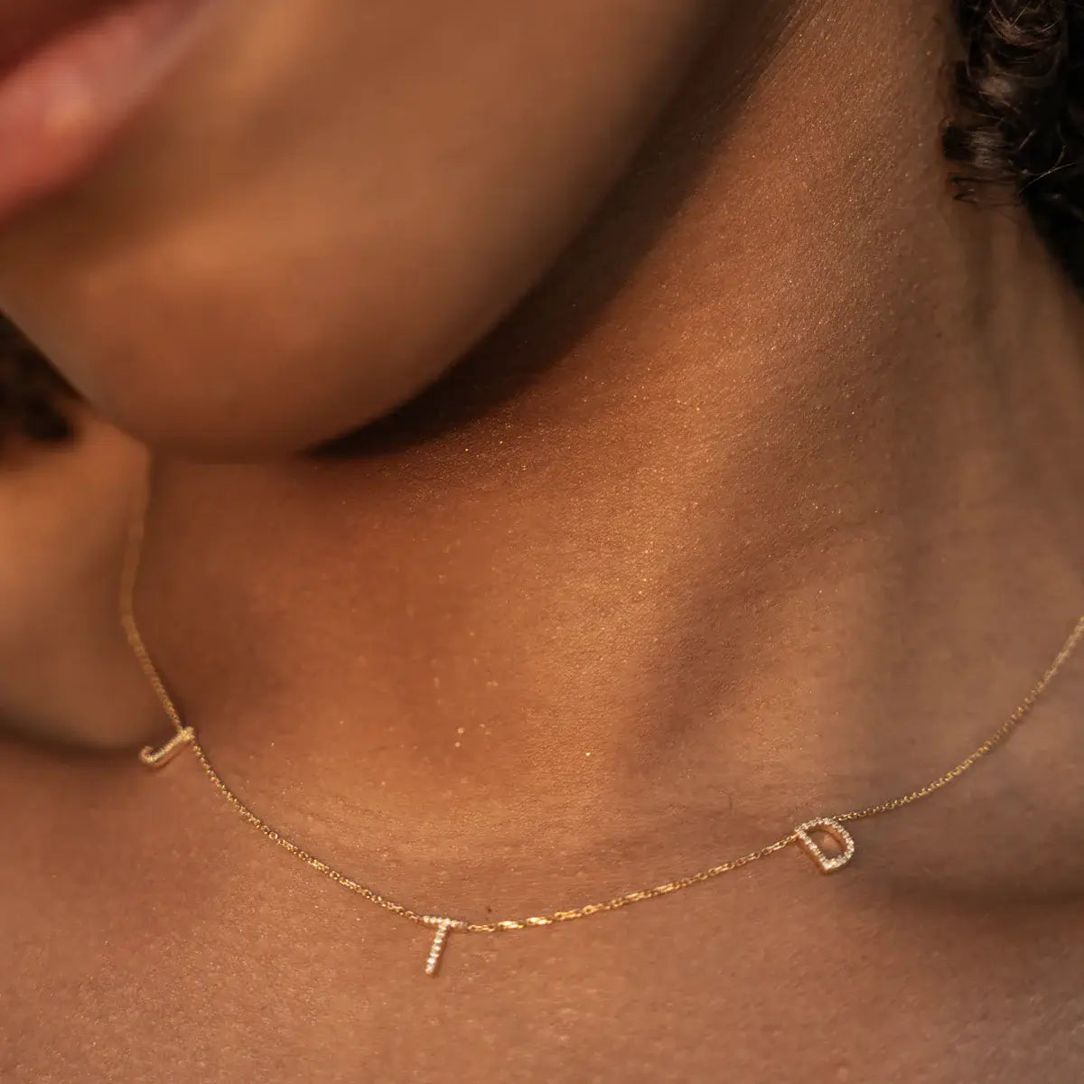 Close-up of a Love Letter necklace with hand-crafted initials and natural diamonds on a fine link chain.