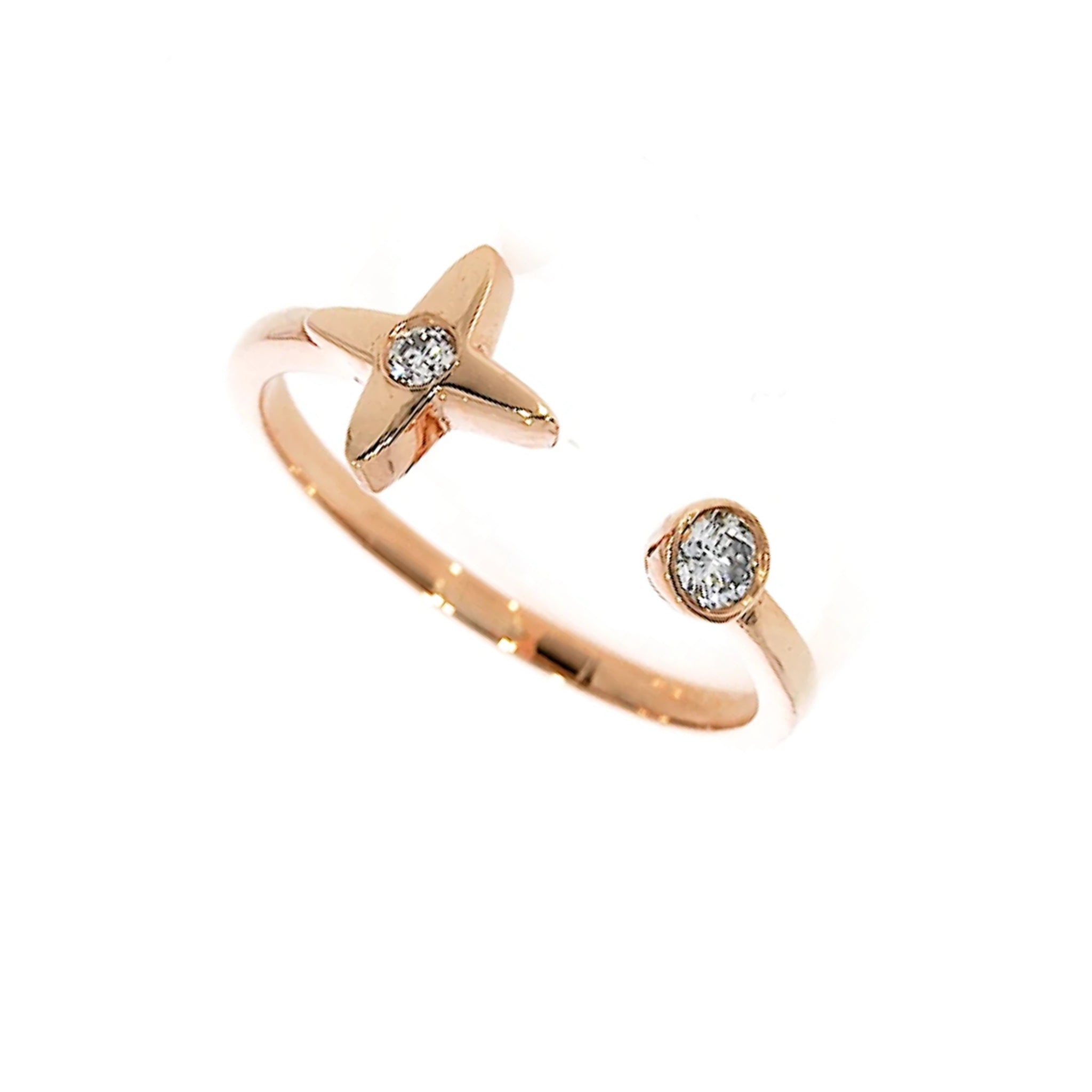 A rose gold open shank ring featuring a four pointed star design on one end with a small round diamond, and a single round bezel set diamond on the other end, shown on a plain white background.
