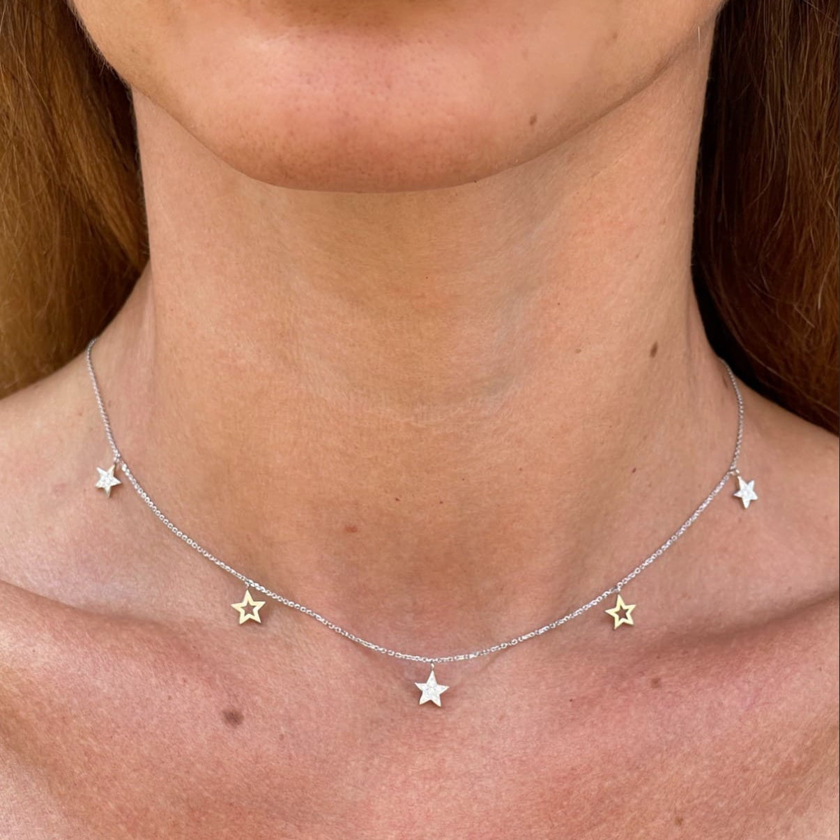 Multi Star Necklace featuring certified diamonds and solid gold stars, elegantly displayed on a woman's neck.