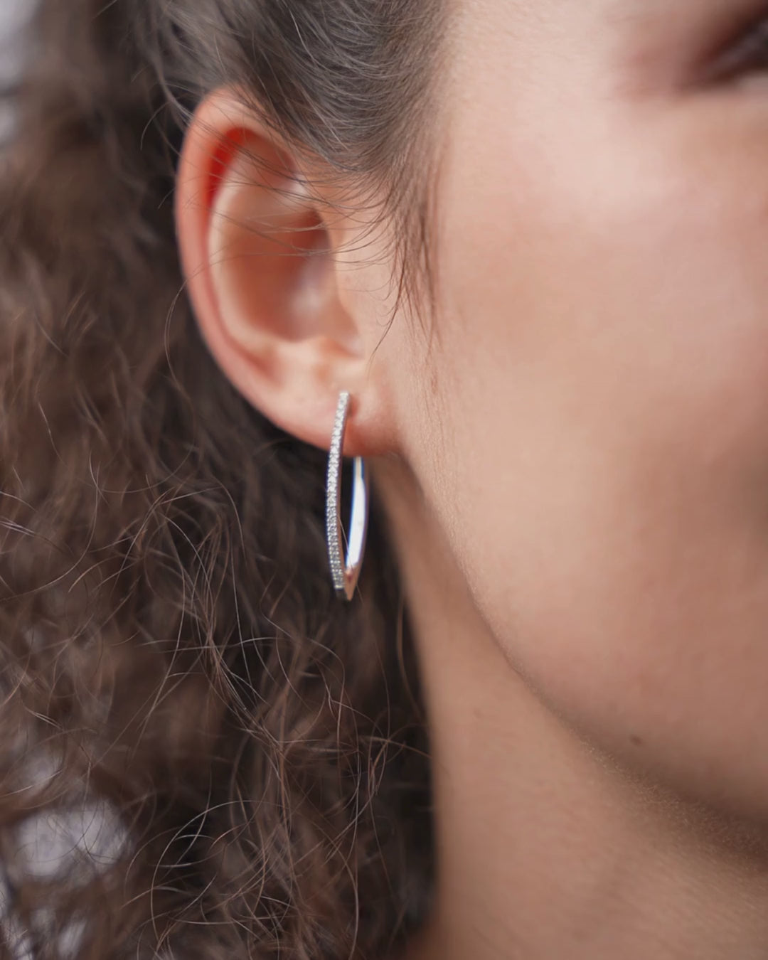 V-shaped certified diamond earrings in 18ct gold displayed on model's ear, highlighting elegant modern design.