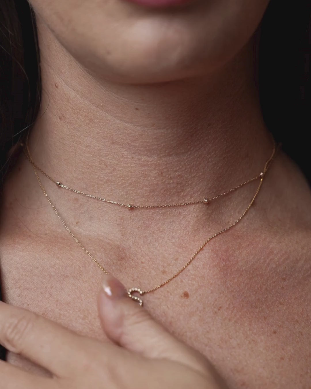 Woman wearing single diamond necklace with certified diamonds featuring a sparkling letter S pendant in gold.