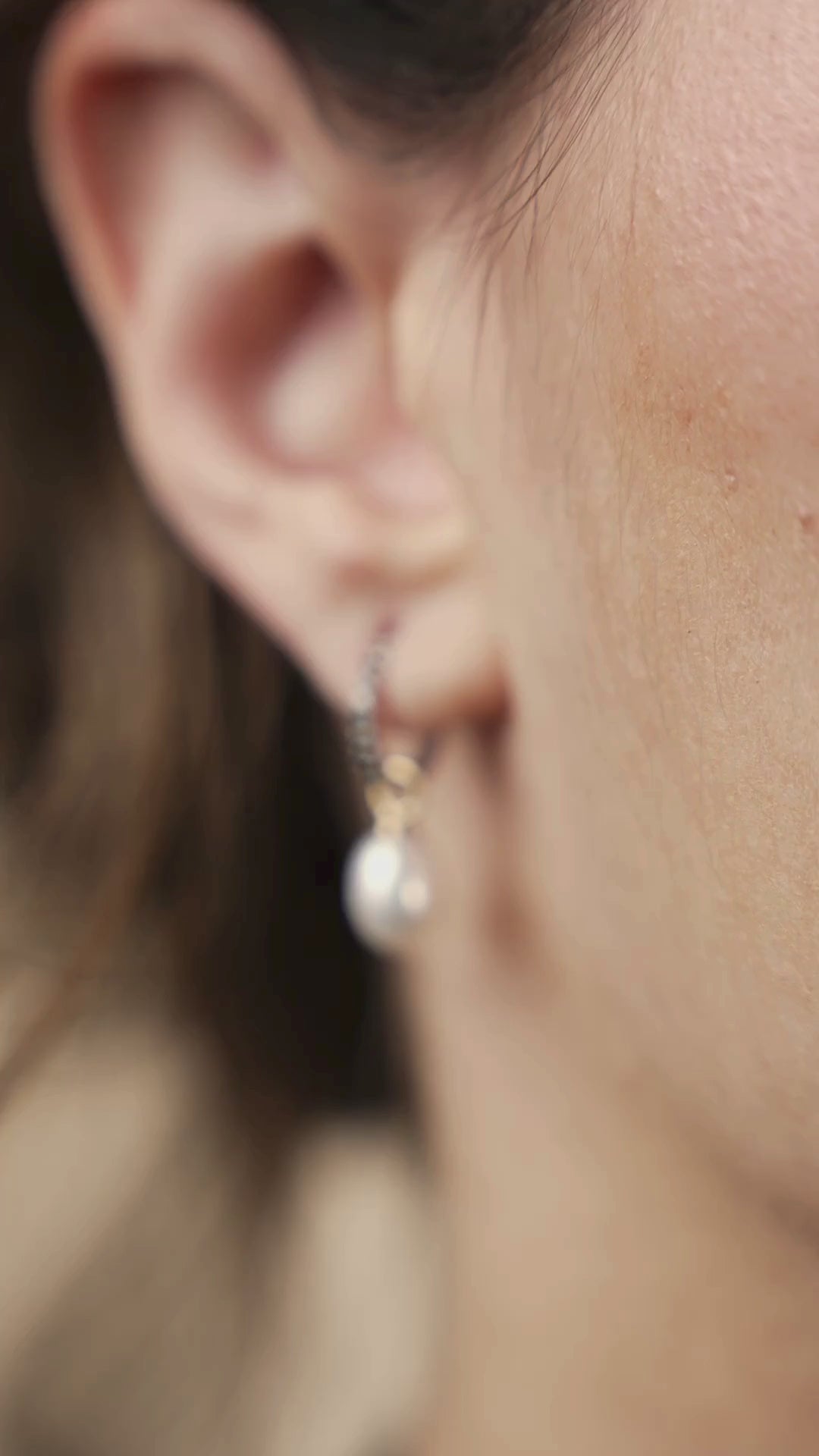 Close up of a woman wearing Lucia diamond earrings with a pearl drop, showcasing elegance and contemporary style.