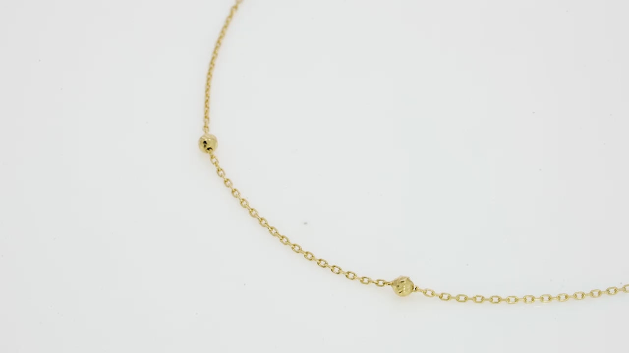 Delicate 18ct gold ball necklace on a plain background, perfect for layering or wearing alone, showcasing subtle texture.