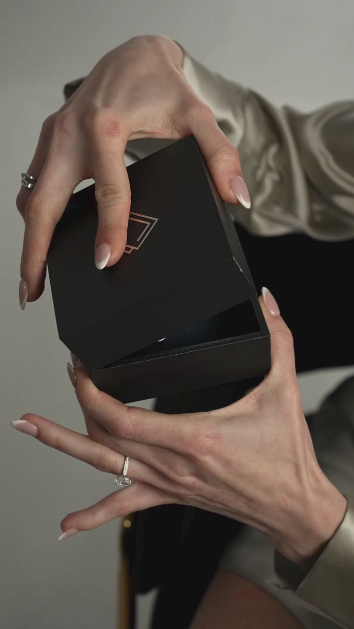 Elegant hands opening a sleek black jewelry box, showcasing a diamond necklace surprise inside.