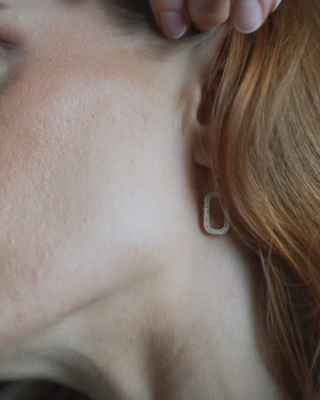 Close-up of a woman wearing gold certified diamond earrings, showcasing their elegance and sparkle.