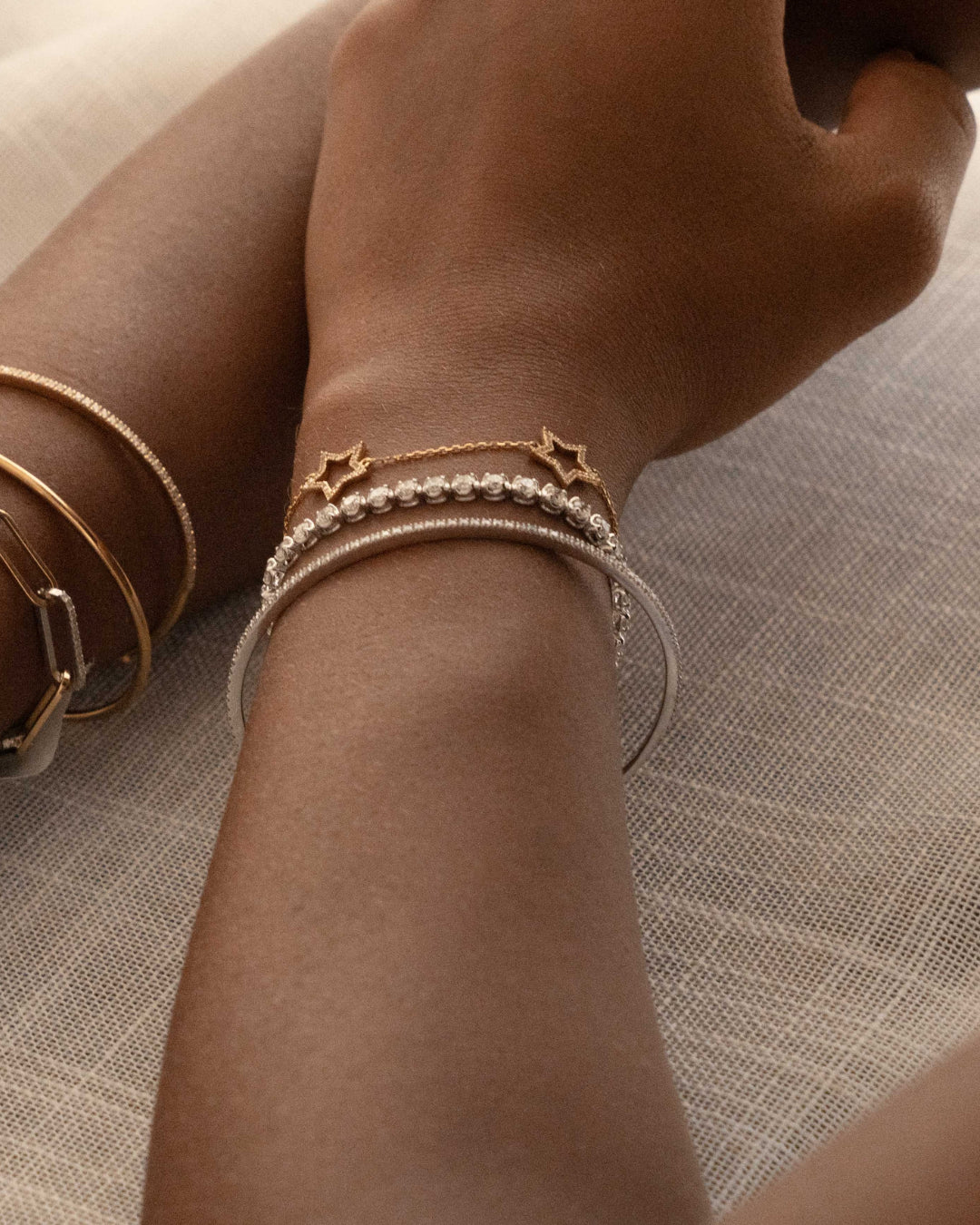 Close-up of a wrist adorned with modern bangles including a tennis bangle with diamonds.