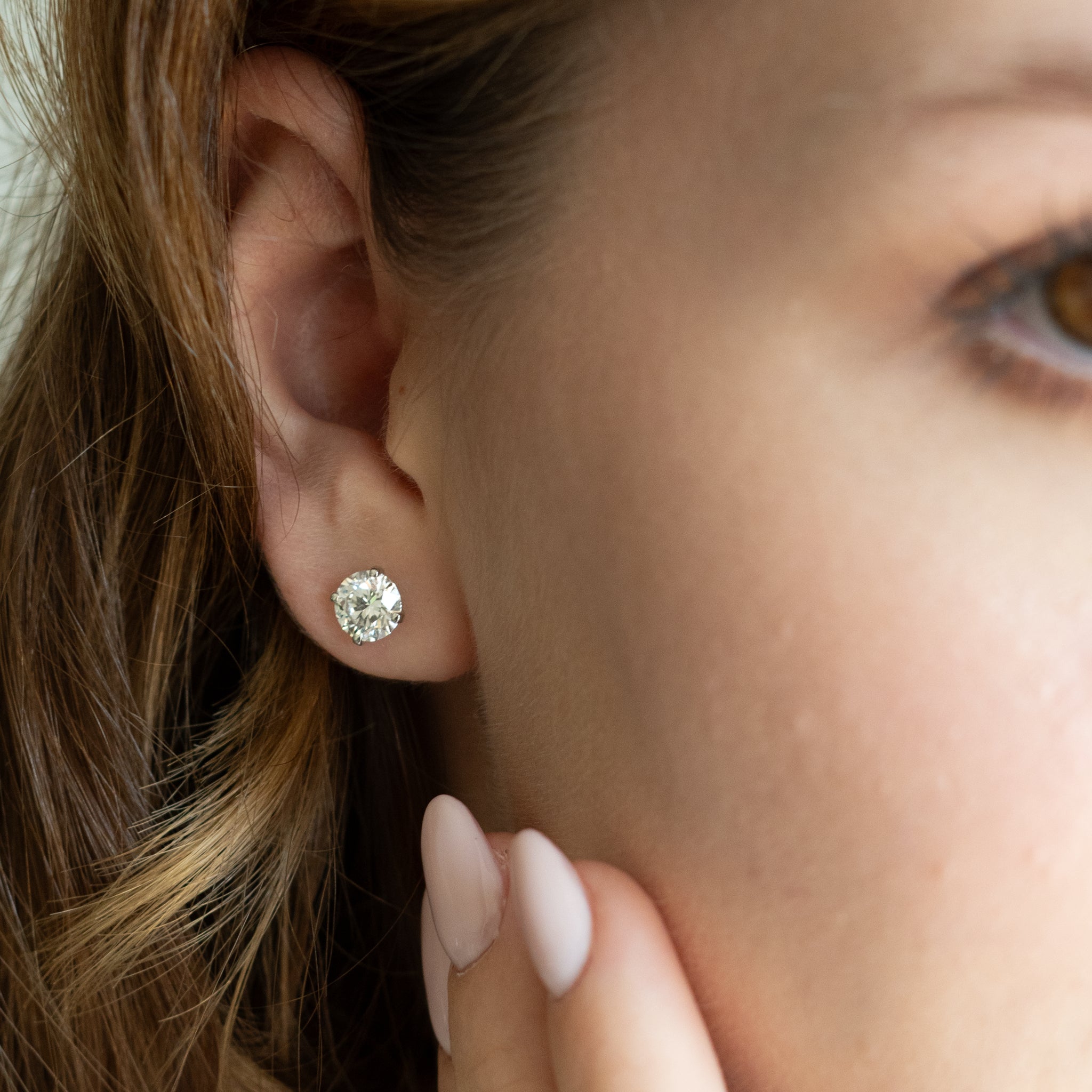 Elegantly displayed certified diamond earrings on a model, showcasing timeless style and brilliance.