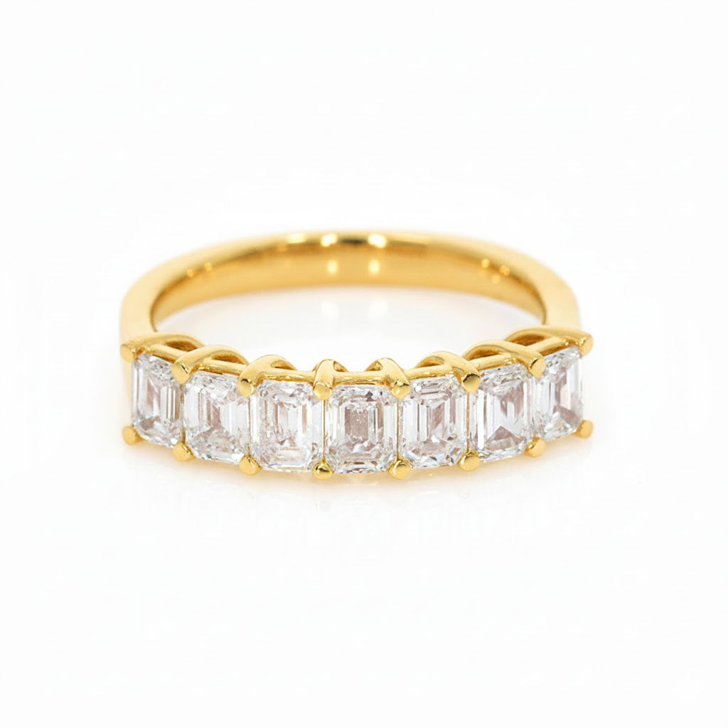 Seven Stone Emerald Cut Diamond Eternity Ring with emerald cut diamonds set in a yellow gold band.