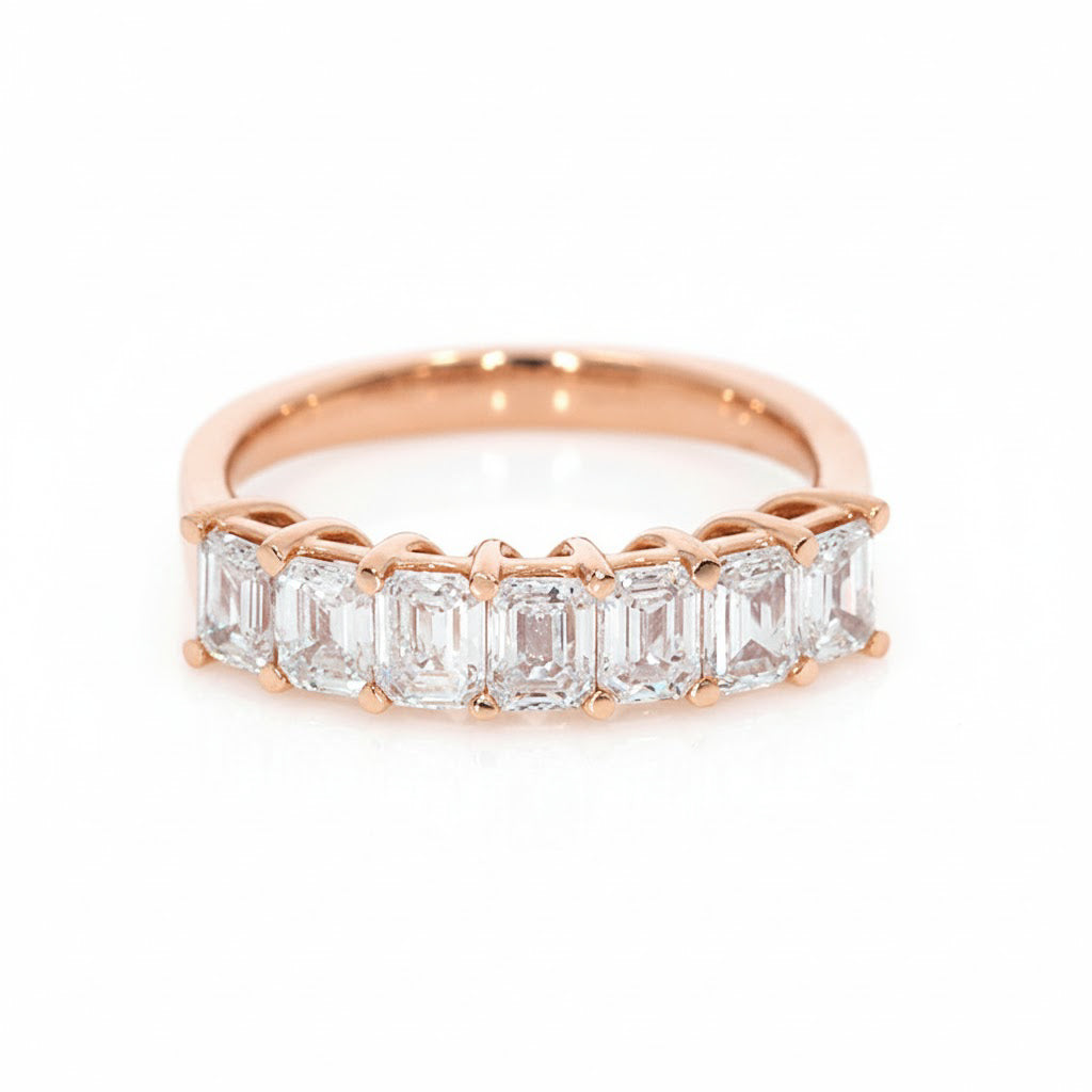 Rose gold ring with emerald-cut diamonds on a white background