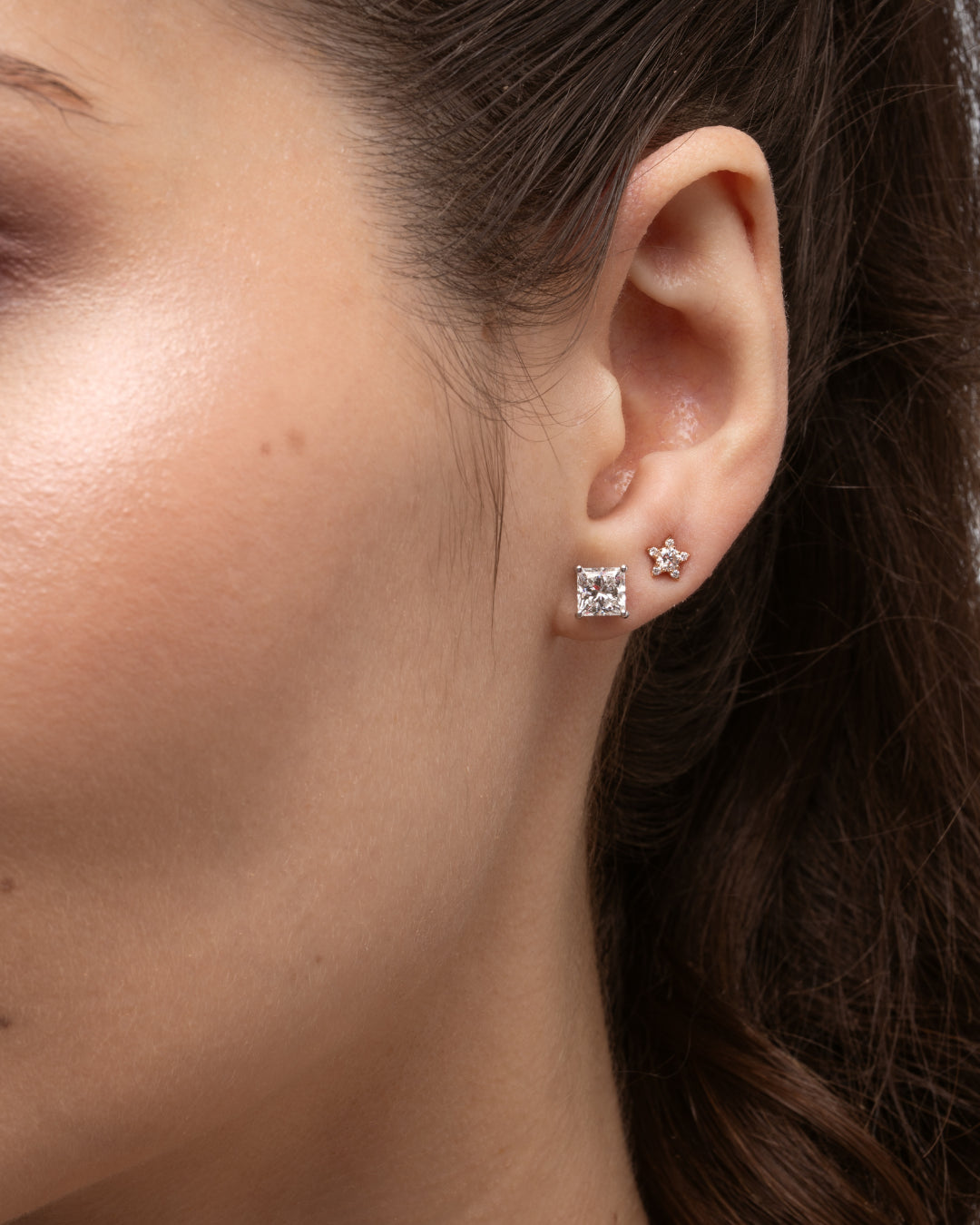 Small star earrings set with certified diamonds showcased on a model's ear, highlighting their elegant sparkle.