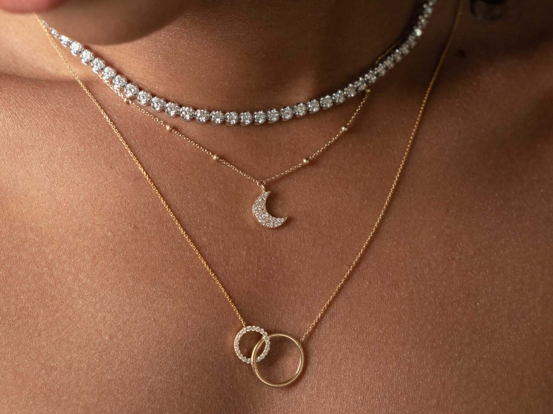 Close-up of layered diamond jewellery necklaces featuring a choker and delicate pendants.