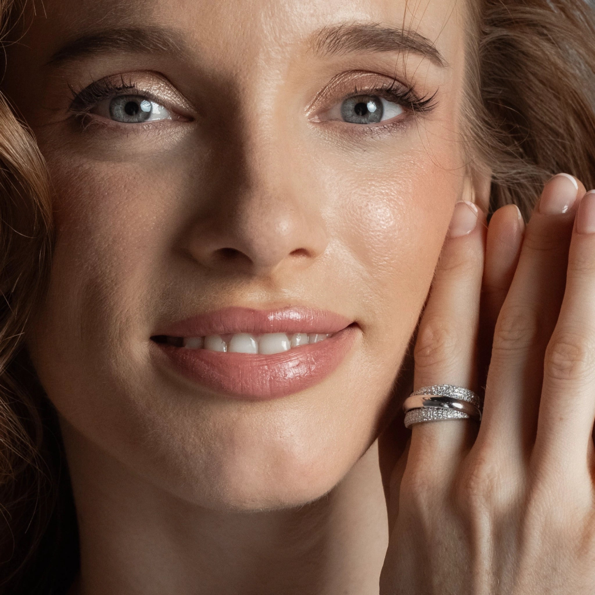 A woman showcasing The Aurora Ring, a gold and diamond ring with overlapping strands, highlighting the beauty of certified diamond rings.