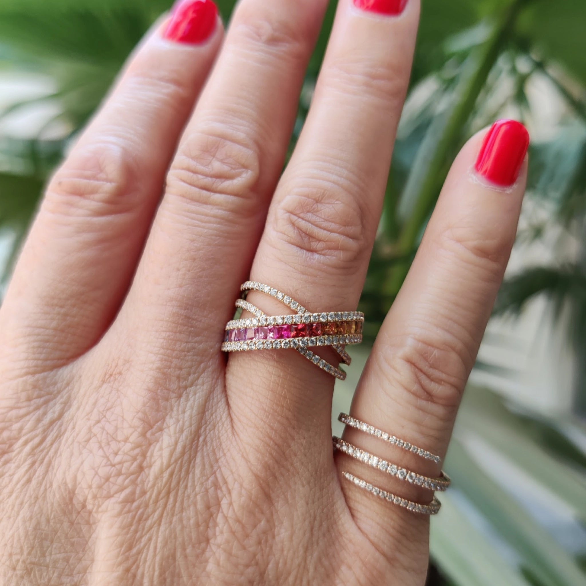 Model wearing Sapphire Criss cross ring featuring fifteen coloured sapphires, and round brilliant diamonds, set in 18ct gold.