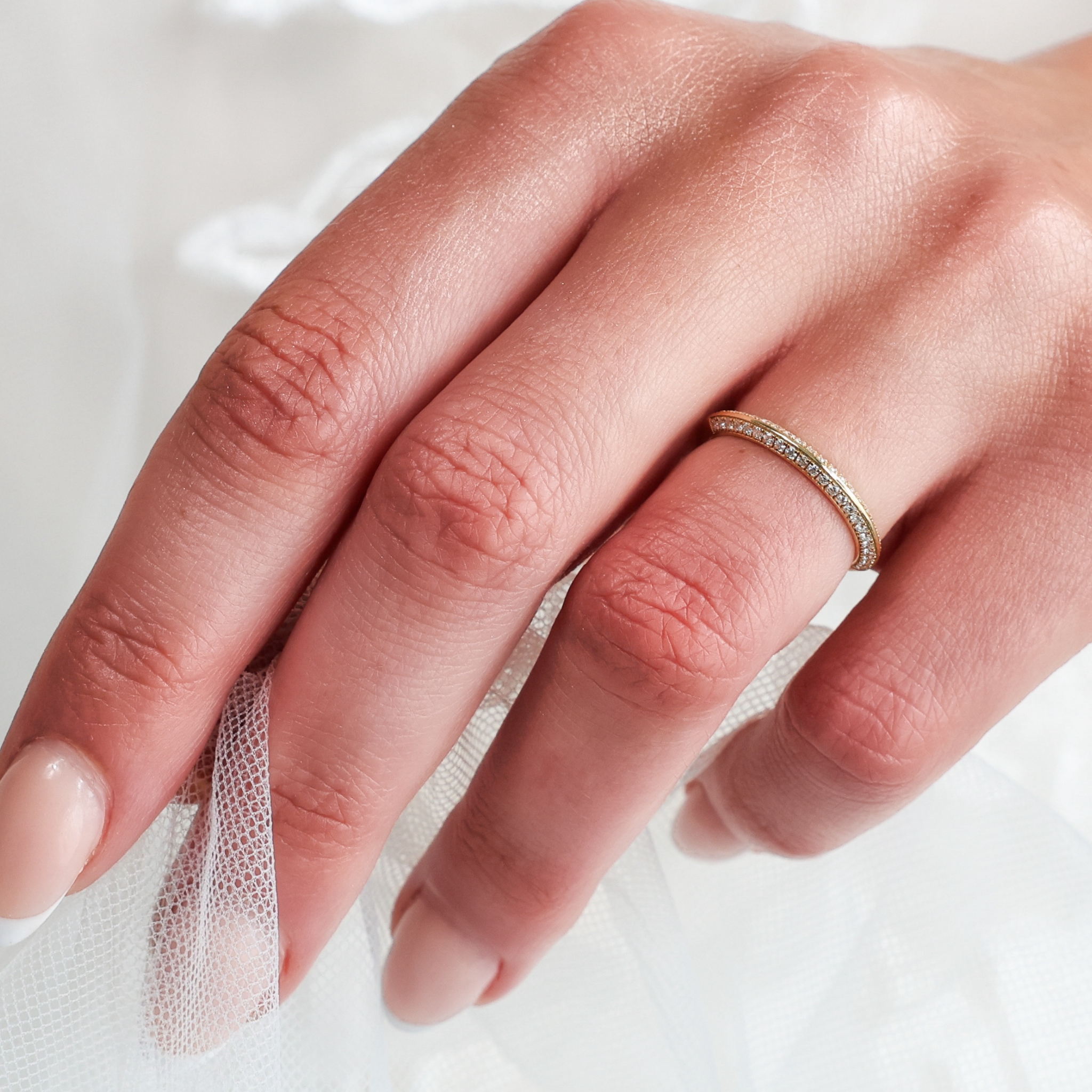 Knife Edge Wedding Band on a hand, displaying delicate micro pavé diamonds and gold craftsmanship.