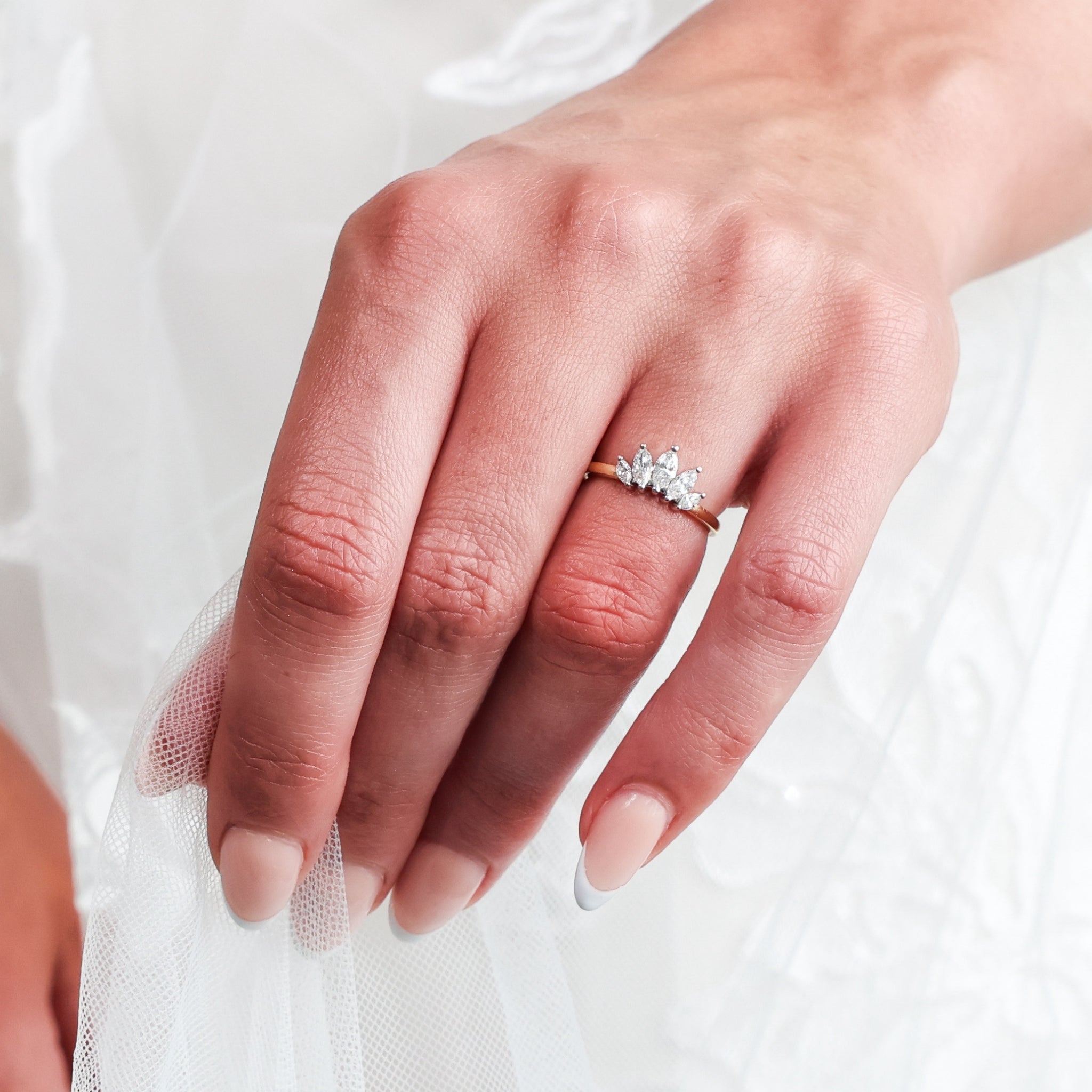 Close up of a hand wearing a Crown Ring adorned with marquise cut diamonds, embodying elegance and sophistication.