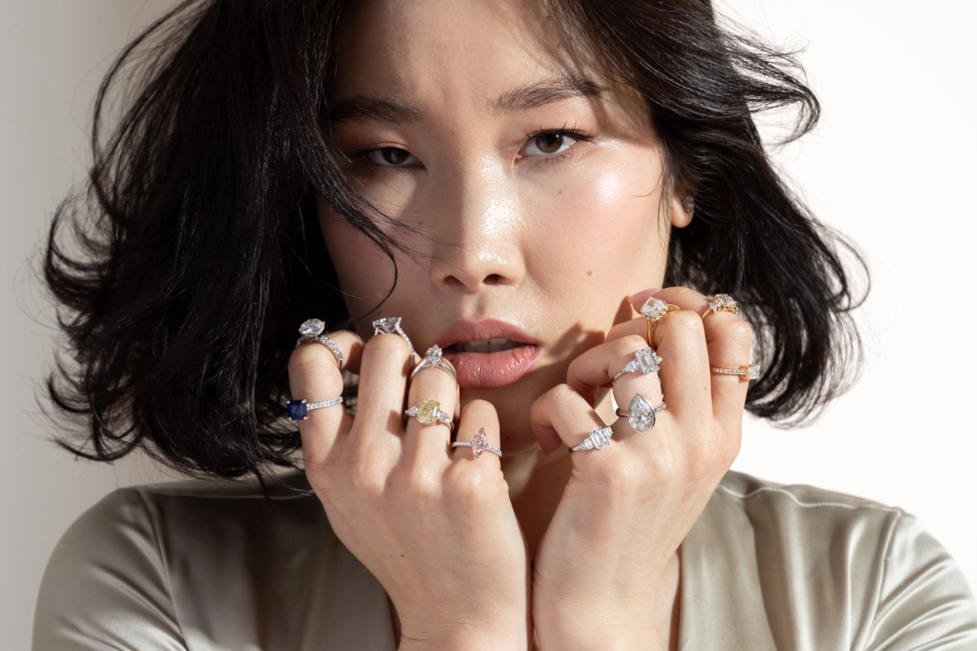 Woman wearing multiple rings on her fingers against a neutral background