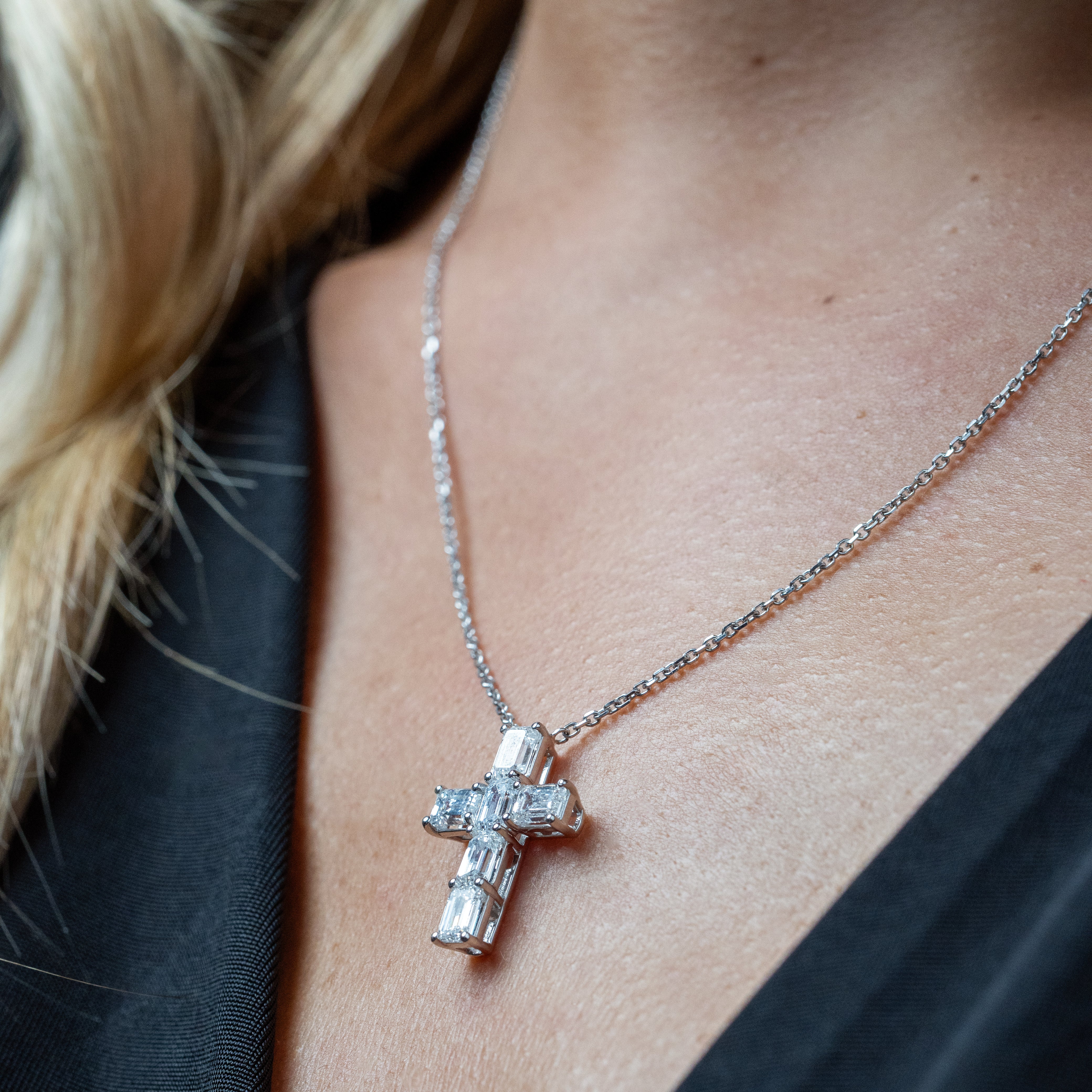 Diamond cross necklace on a person wearing a black top