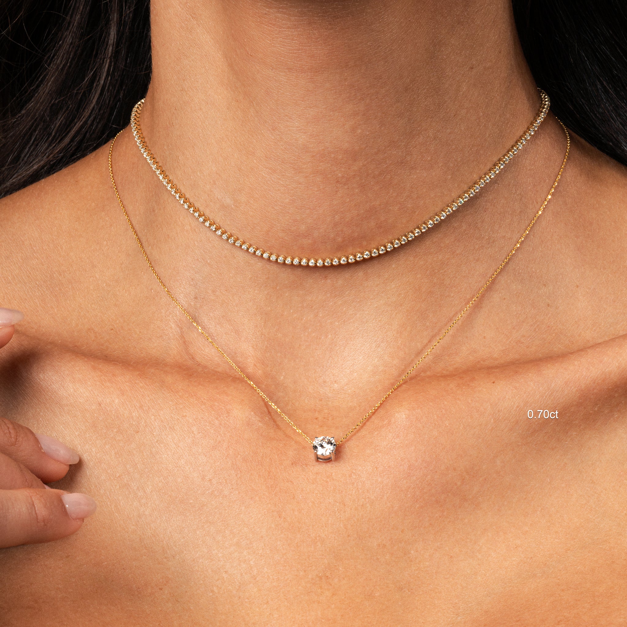 The Floating Diamond Necklace featuring a round brilliant cut diamond on a fine gold chain, worn with a choker.