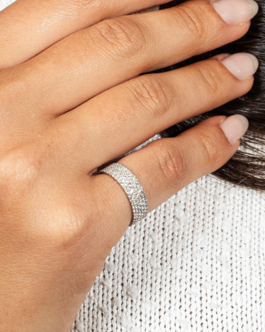 Four row pavé diamond ring on a hand, showcasing round brilliant cut diamonds in modern luxury design.