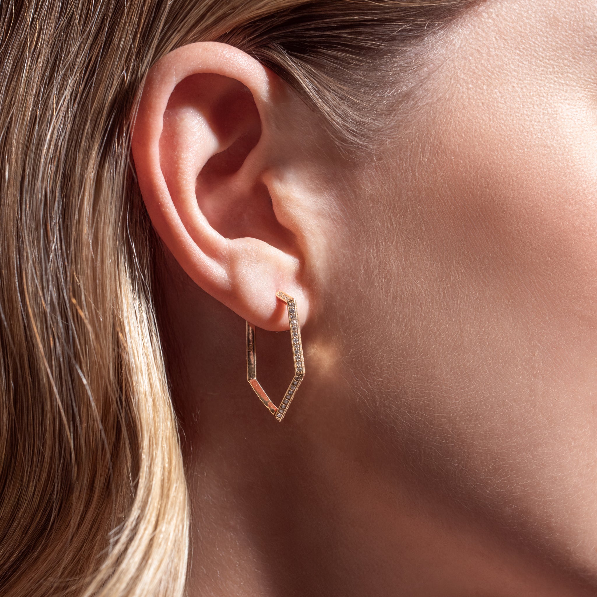 Rose gold hoop diamond earrings worn by a person with blonde hair