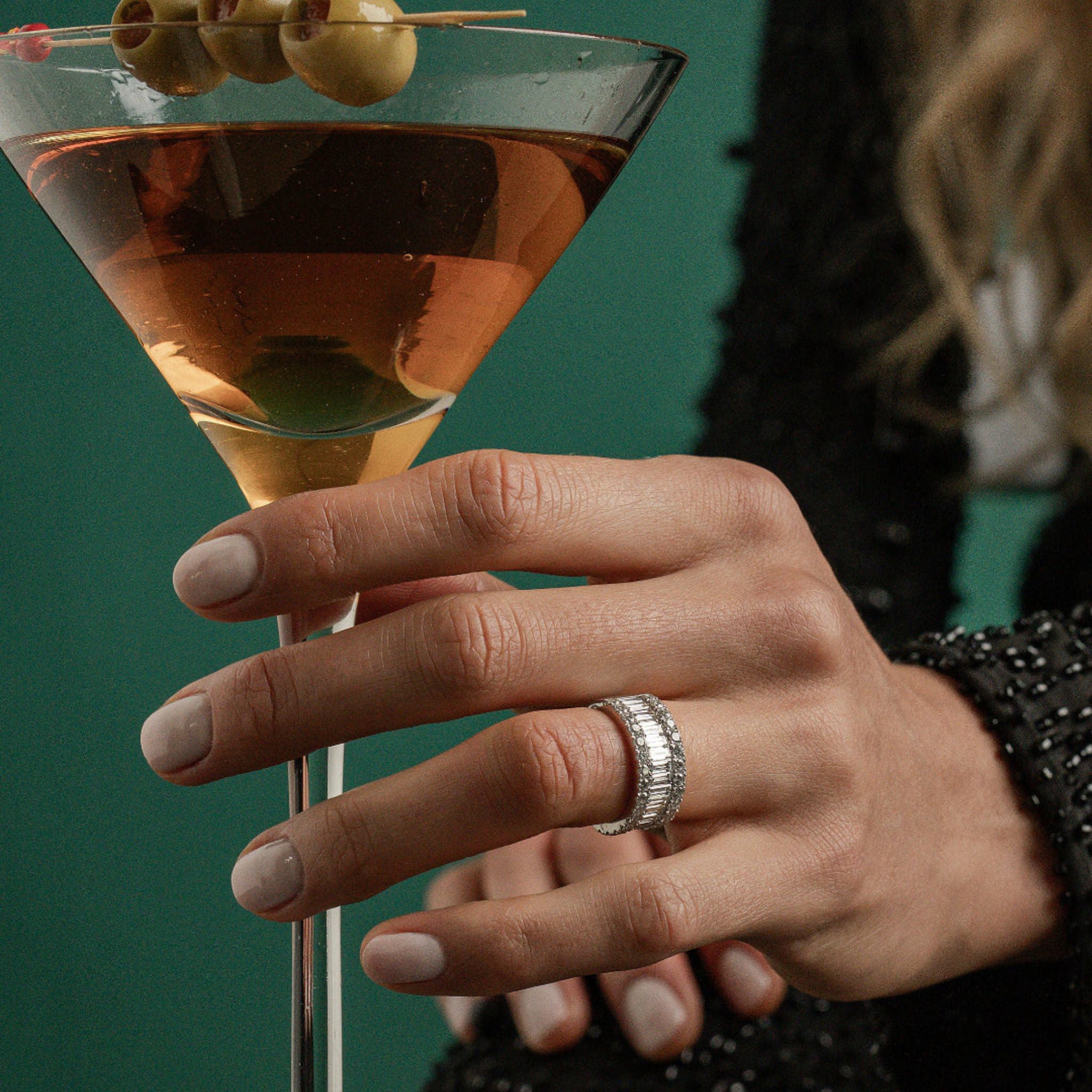 Close-up of a hand wearing a large diamond eternity ring with a green background