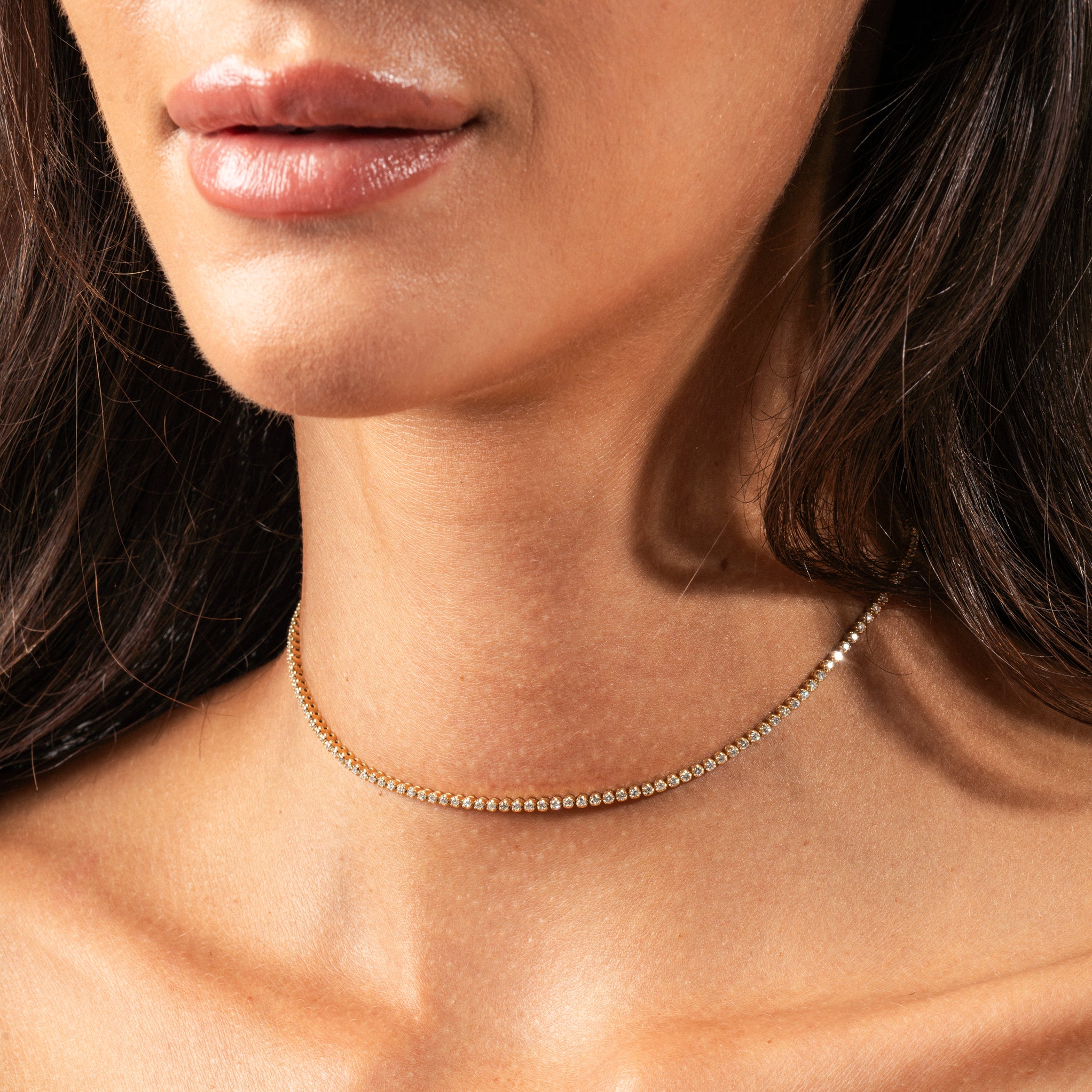 Close-up of a woman wearing a Maia certified diamond necklace showcasing round brilliant cut diamonds