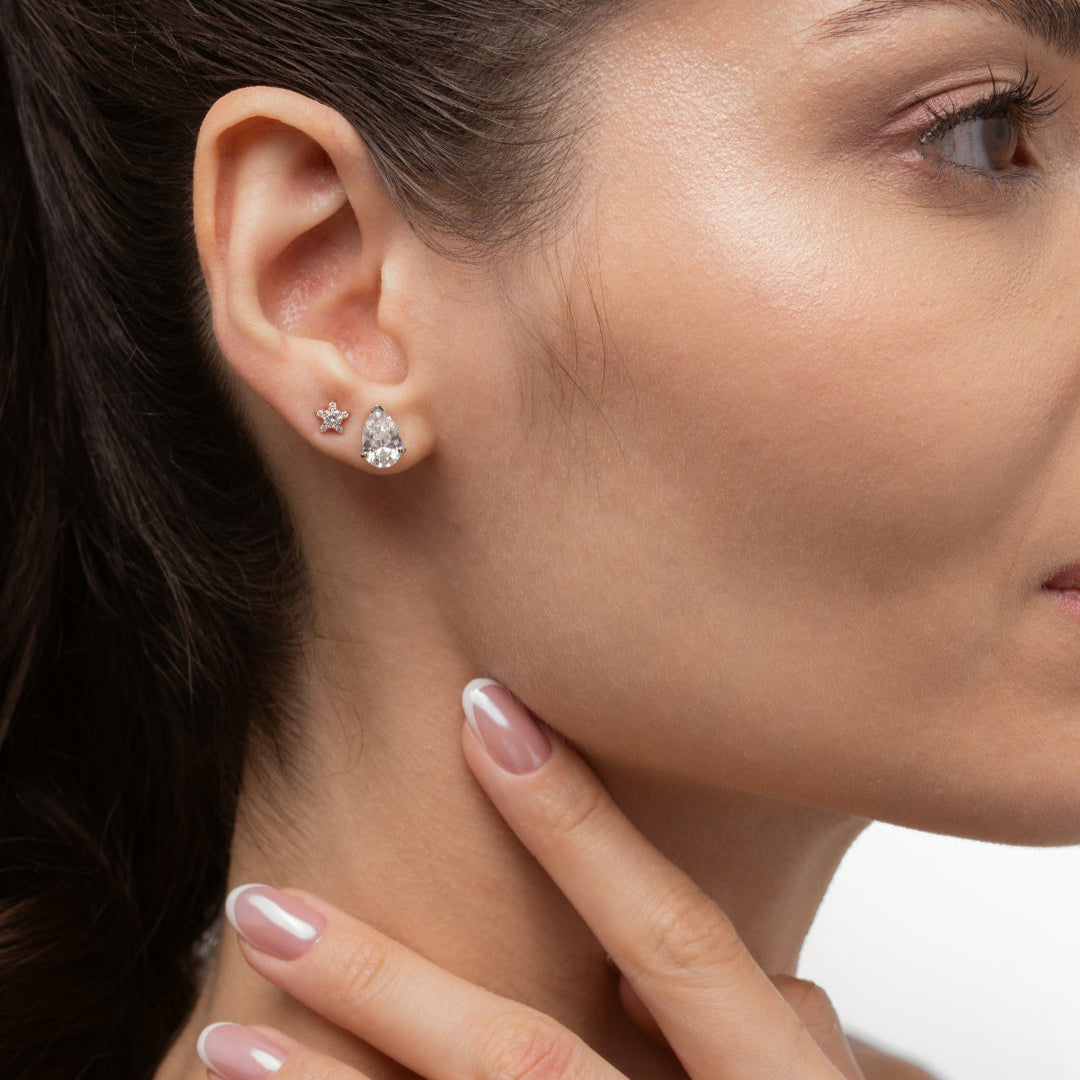 Model showcasing Pear Diamond Stud Earrings and a star-shaped earring, highlighting luxurious diamond earrings.