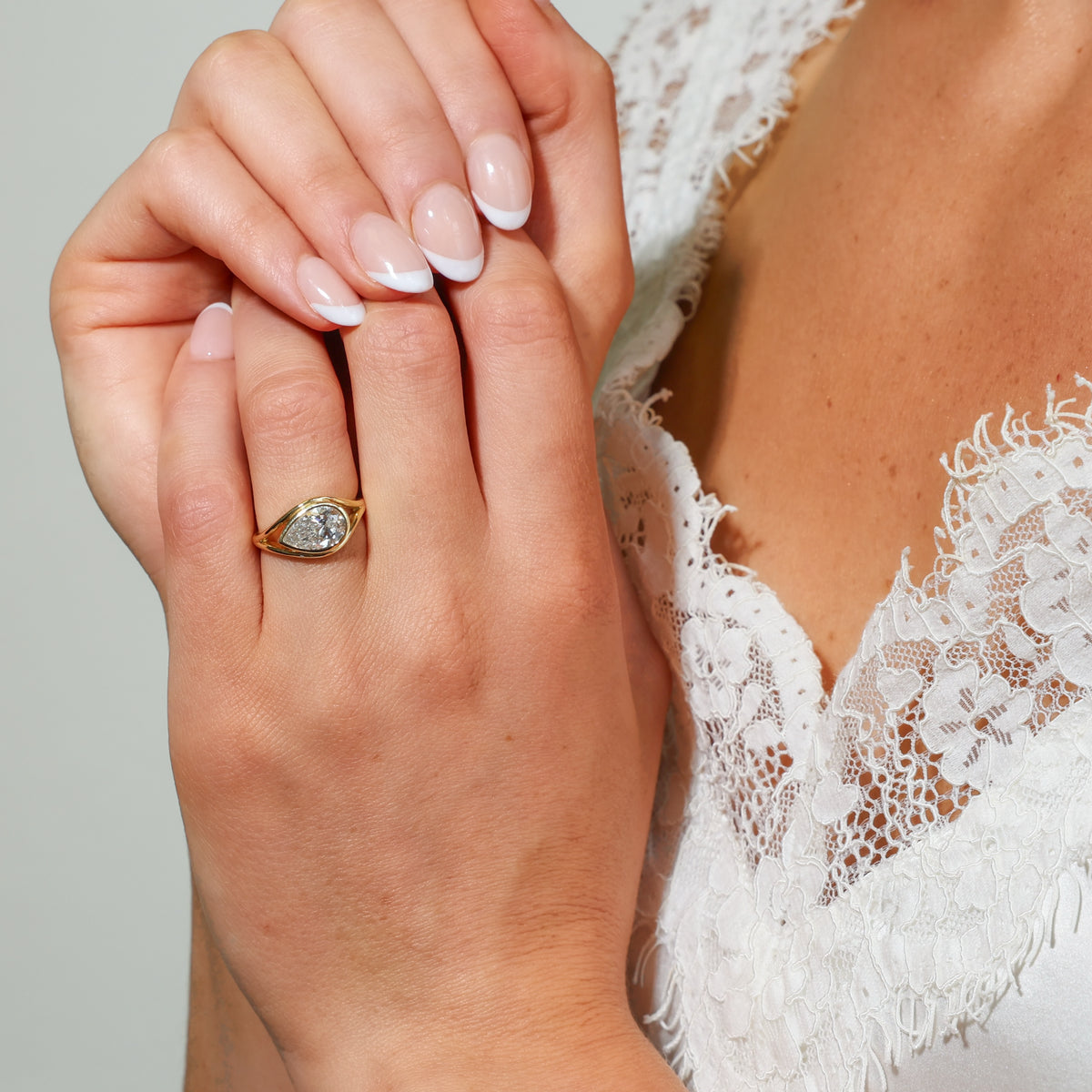 Beautiful hand wearing a pear shaped ring set in 18ct yellow gold, showcasing a pear cut diamond.