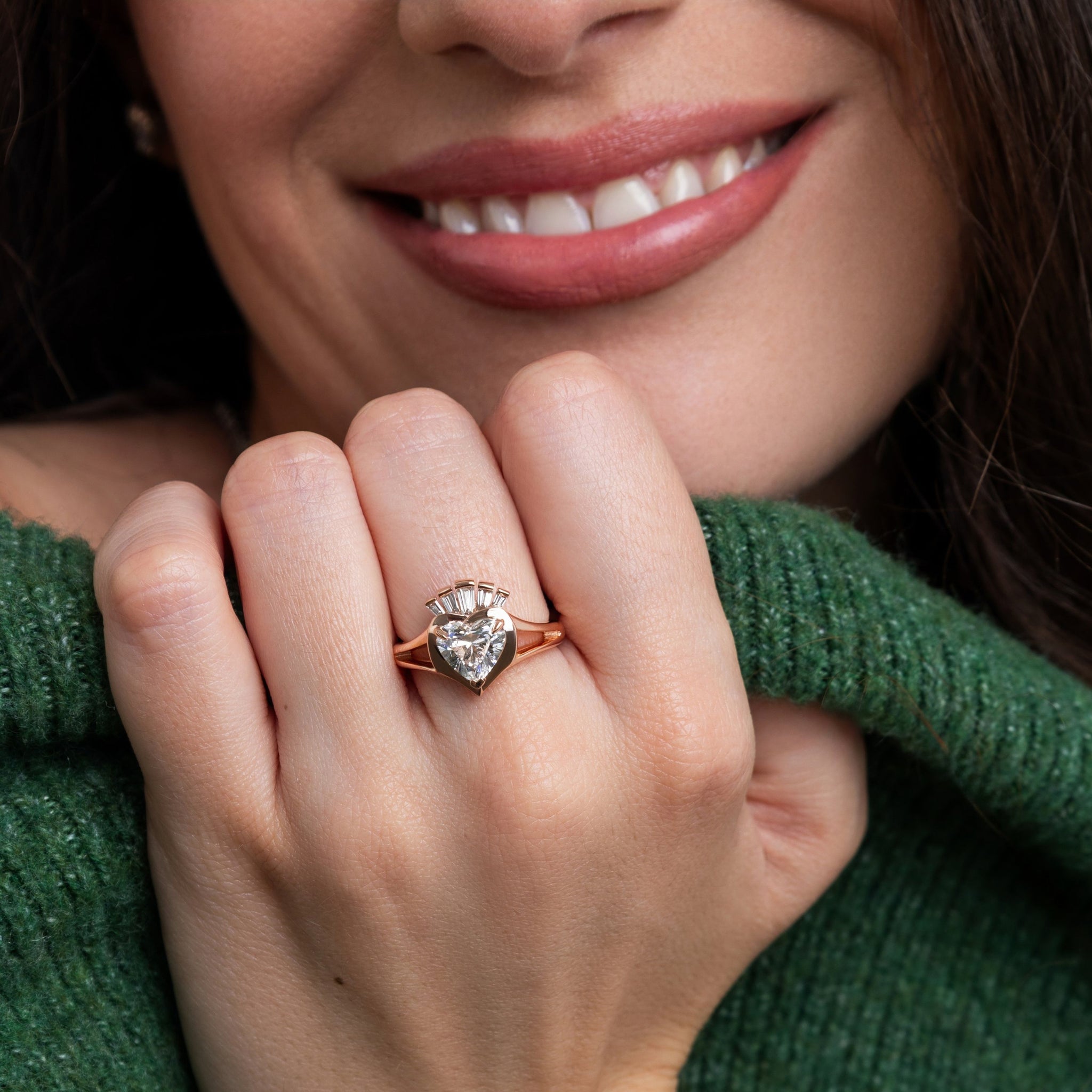 Close-up of a woman's hand wearing a rose gold claddagh ring with diamonds