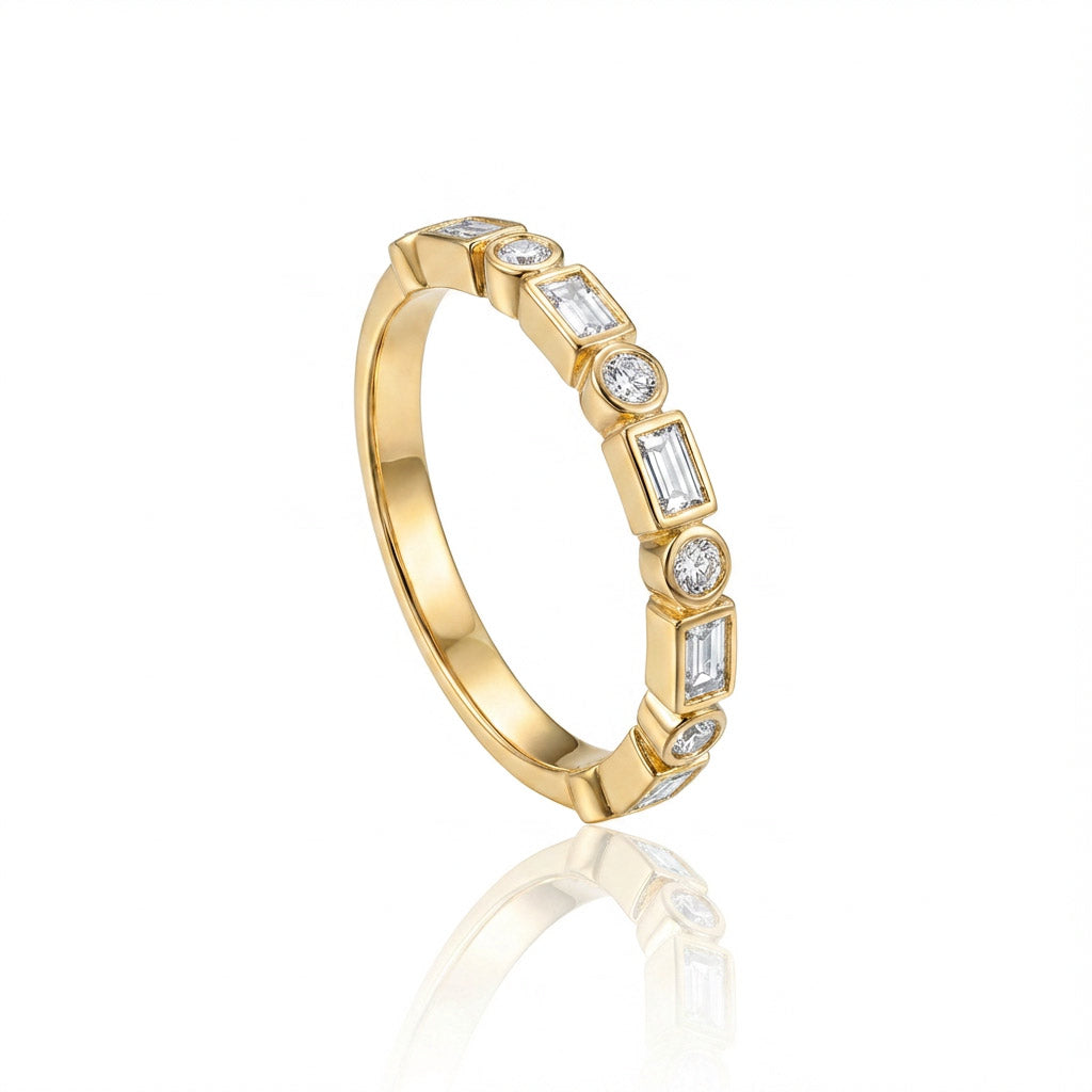 A yellow gold eternity style ring featuring  round cut  diamonds with emerald cut diamonds shown on a clean white background with a soft reflection below.