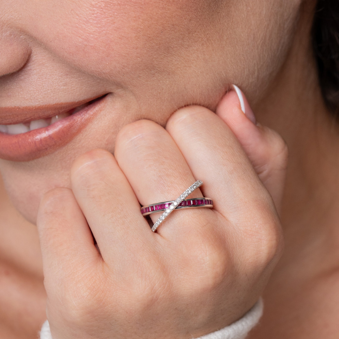 Close-up of a woman wearing a ruby criss cross ring featuring red rubies and diamonds, showcasing a vibrant gemstone ring.