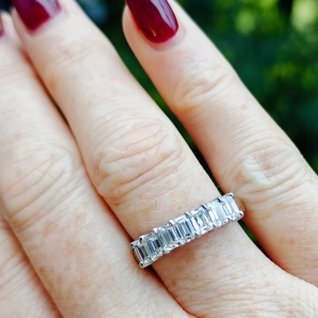 Seven stone emerald cut diamond eternity ring showcasing its brilliance and elegance on a hand.