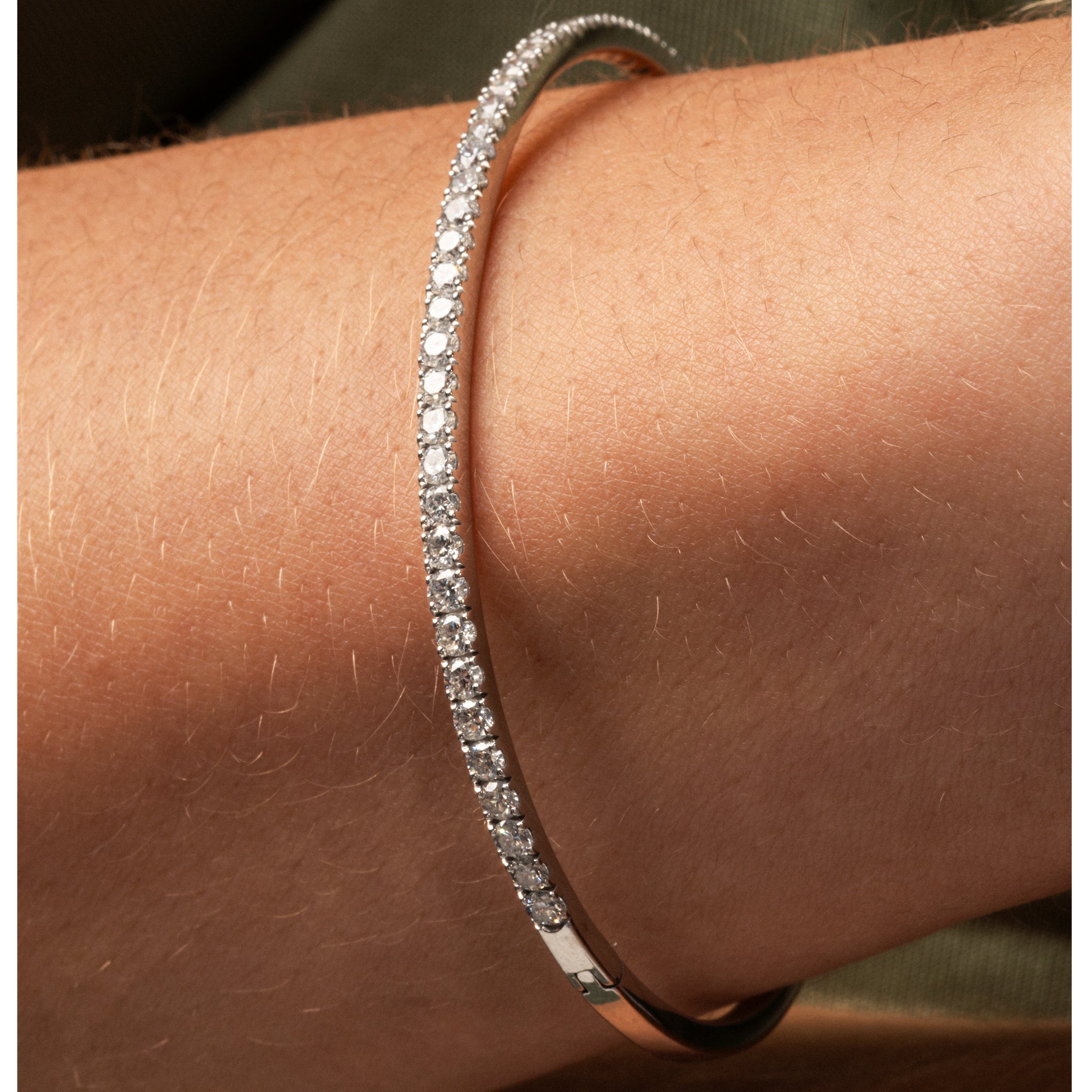 Diamond tennis bangle featuring diamonds set in solid 18ct gold worn on a wrist.