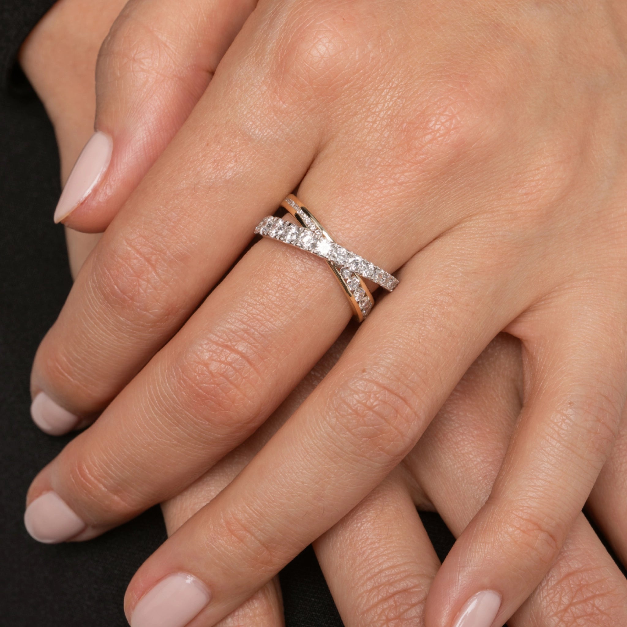 Close-up of a hand wearing a diamond ring on a dark background